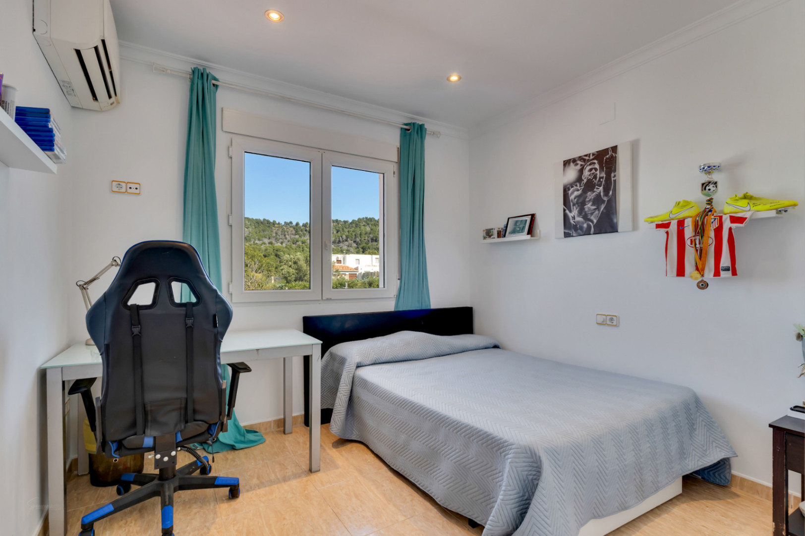Bright bedroom featuring a dedicated workspace, split air conditioning, and a PVC window offering clear views of the Mediterranean landscape.