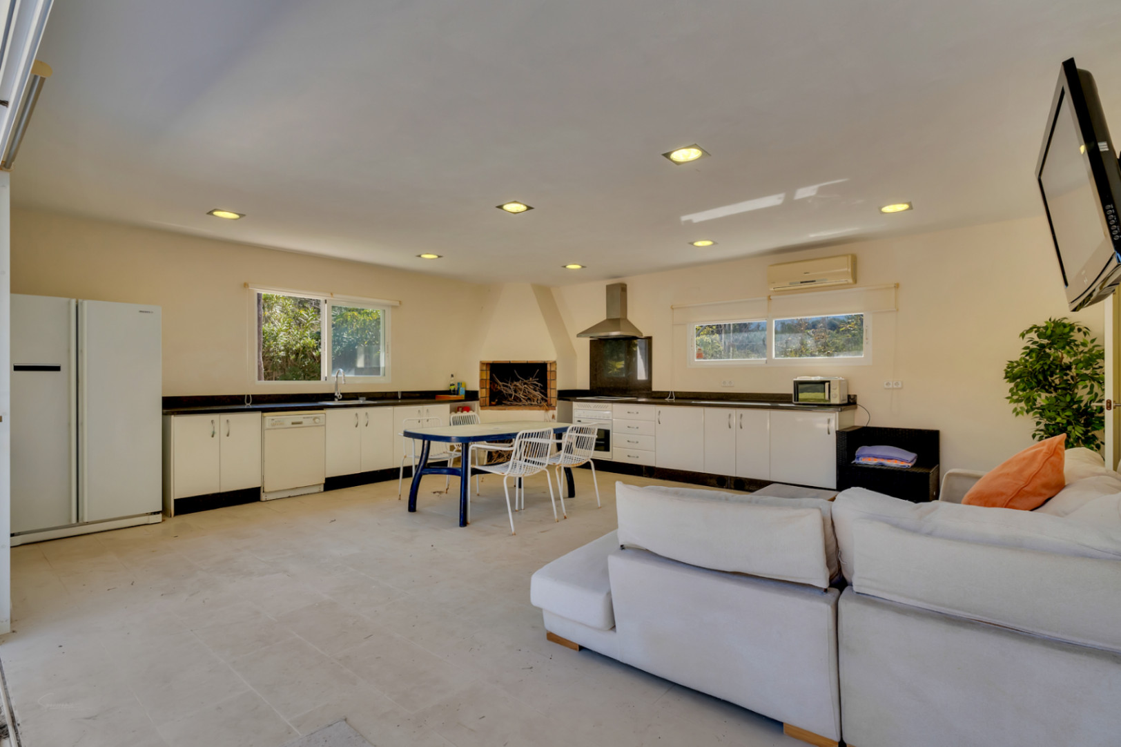 Spacious 67 m² covered barbecue area featuring a full kitchen with granite countertops, fireplace, dining set, and air-conditioned lounge.