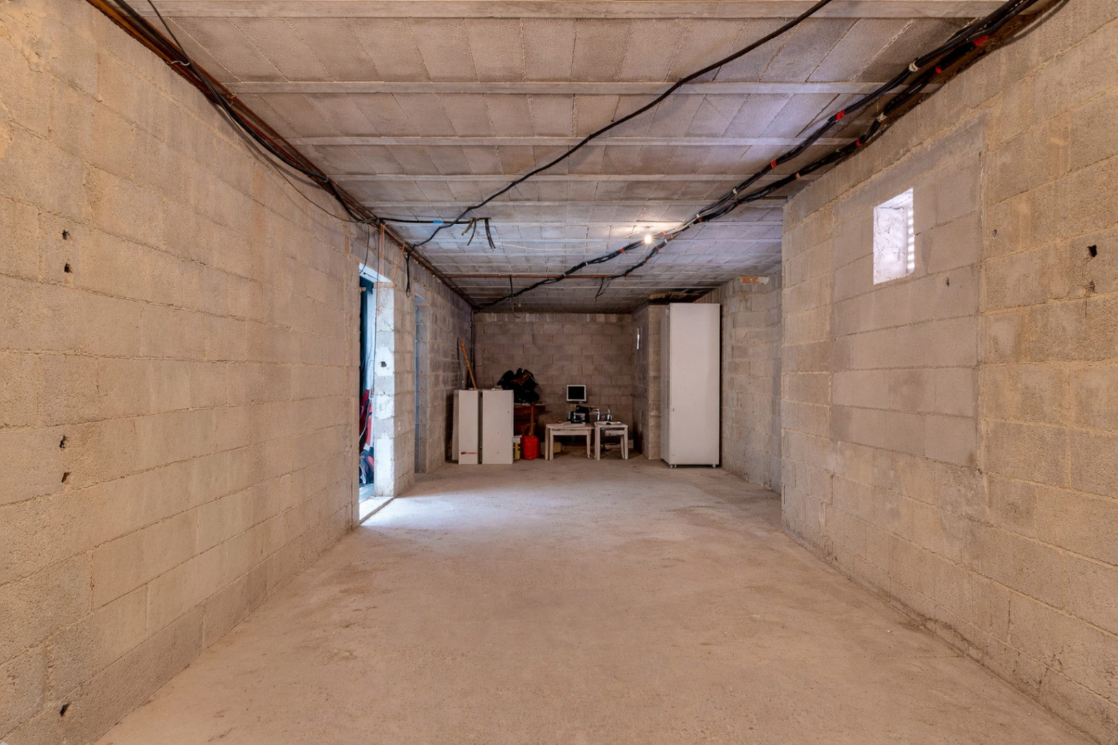 Spacious unfinished lower level with concrete block walls and high ceilings, providing a versatile area for additional bedrooms or a guest apartment.