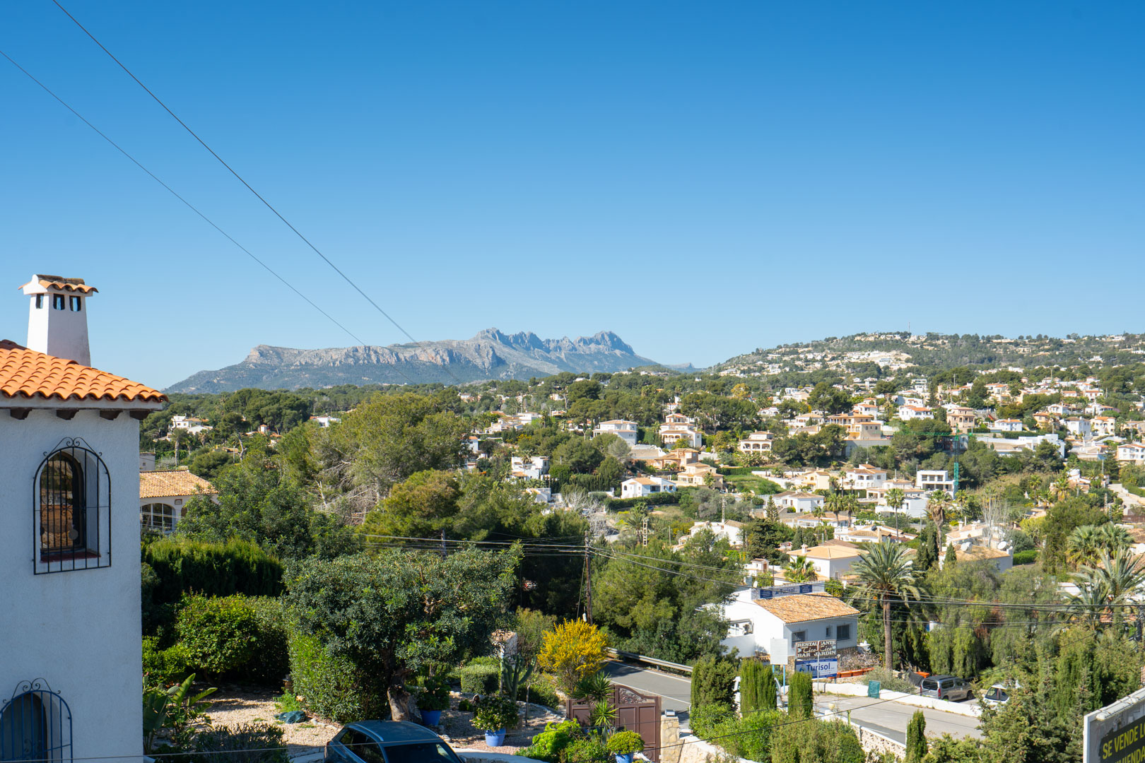 Clear views from the upper terrace towards the Sierra de Bernia mountains, overlooking the residential surroundings and lush Mediterranean greenery.