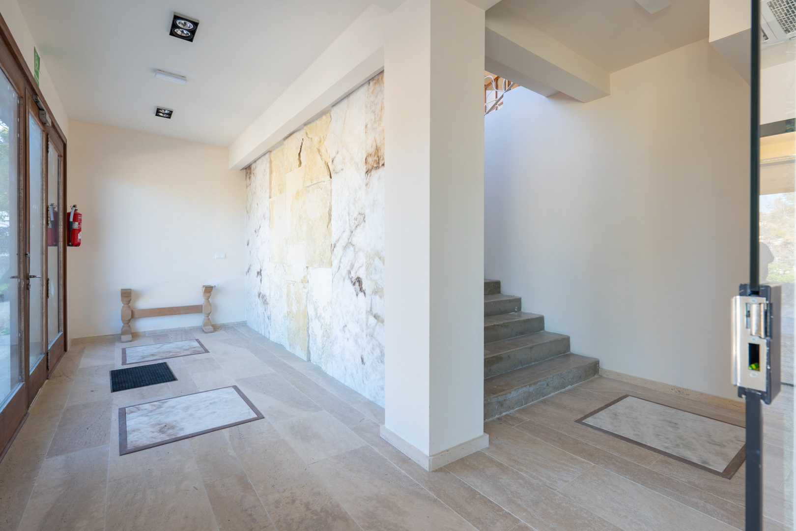 Entrance hall featuring a natural stone accent wall, tiled flooring with marble insets, and a staircase leading to the upper levels.