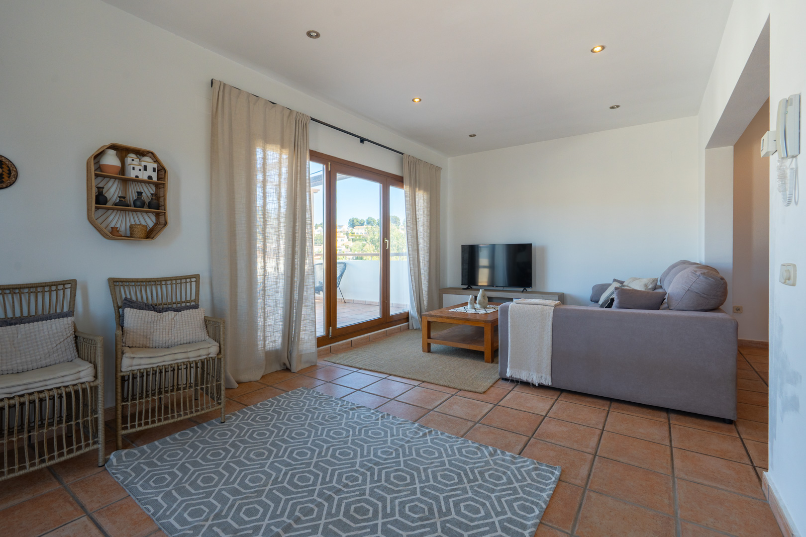 Living area featuring terracotta tile flooring, recessed ceiling lighting, and large sliding doors opening onto a private terrace.