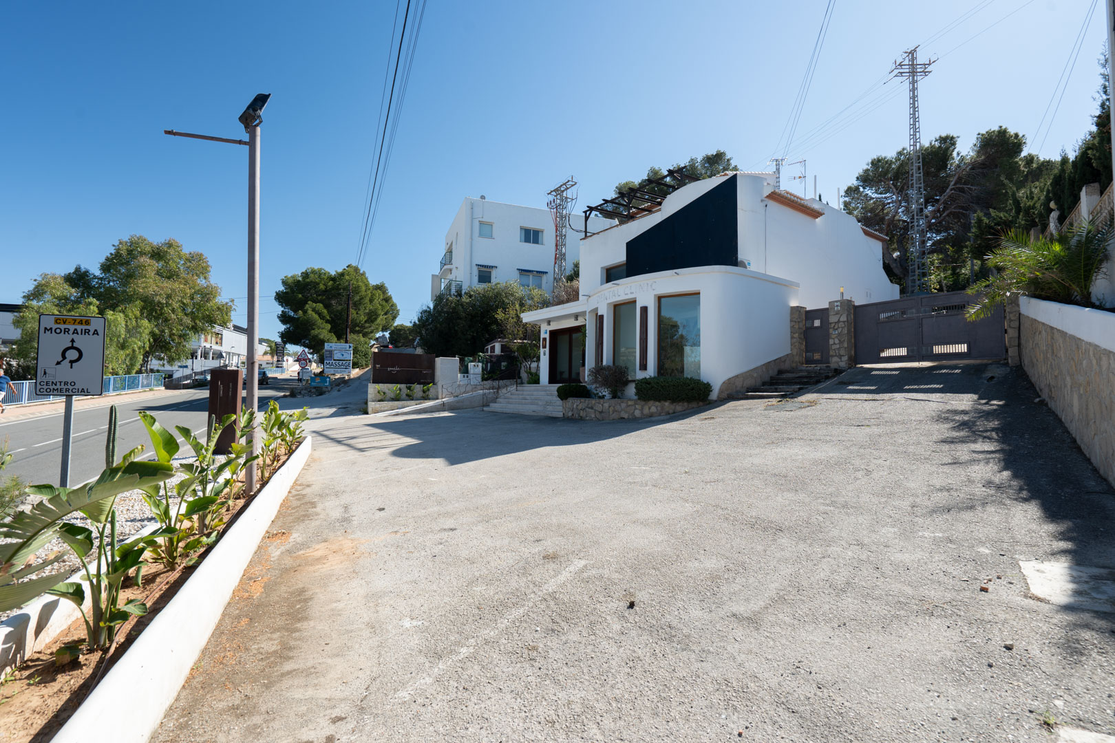 Modern exterior facade featuring large display windows, a spacious private parking area, and direct access from the main Moraira-Calpe road.