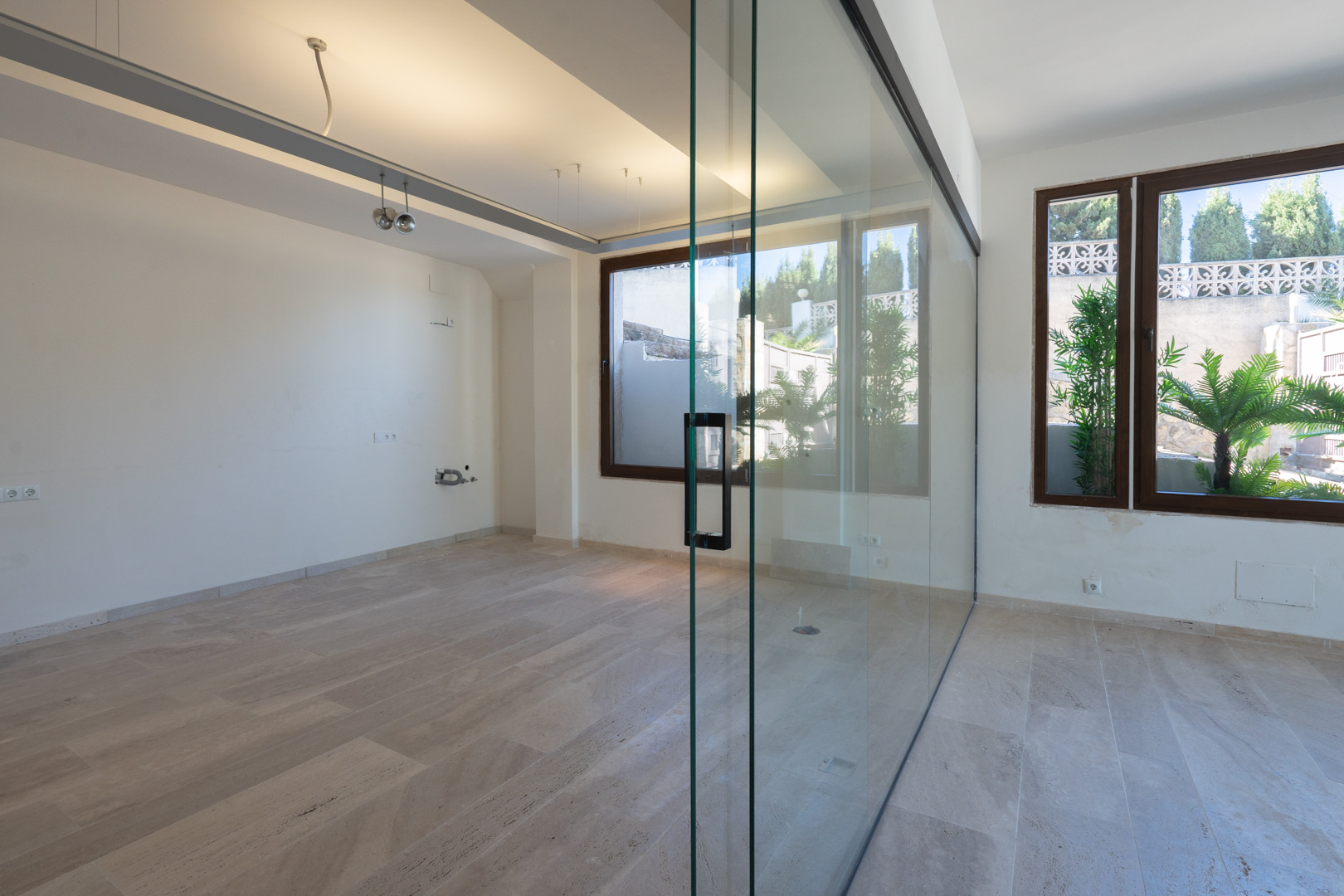 Open commercial area featuring natural stone flooring, white walls, and a large glass partition wall that maximizes natural light and visibility.