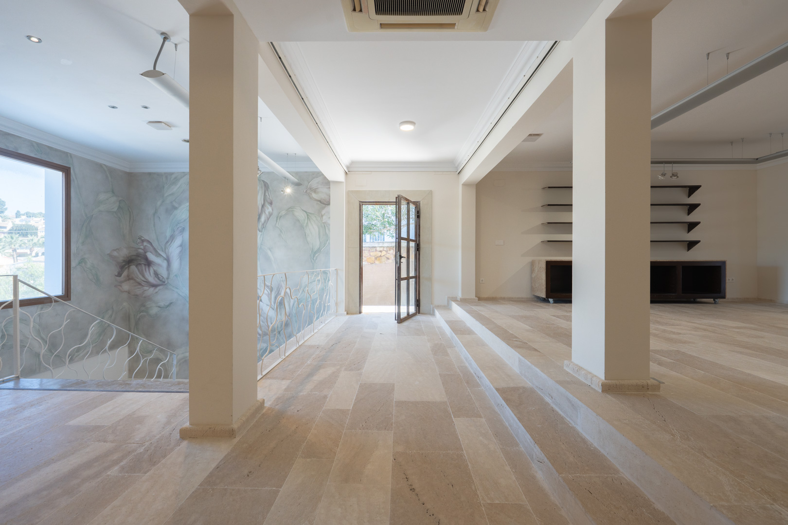 Spacious commercial level featuring stone flooring, an artistic floral mural, and white wrought iron railings. Includes central air conditioning and outdoor access.