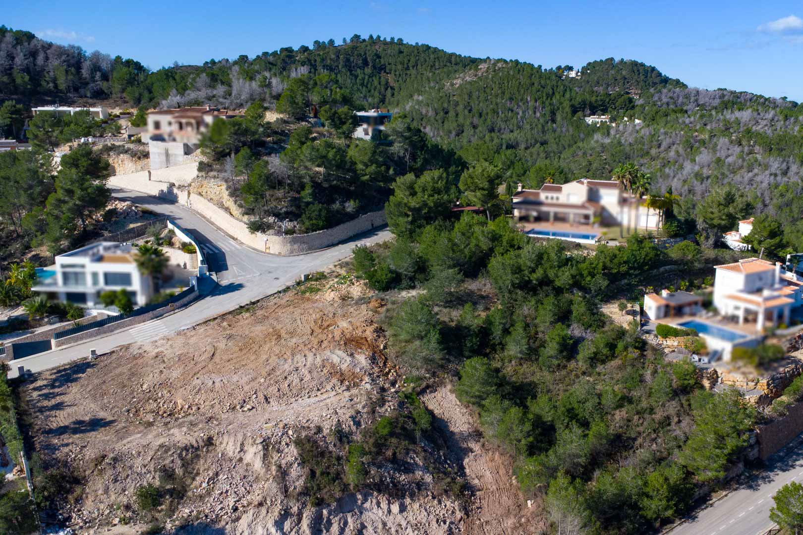 Aerial view of the elevated plot surrounded by pine forests, featuring the prepared construction site and neighboring villas with private pools.