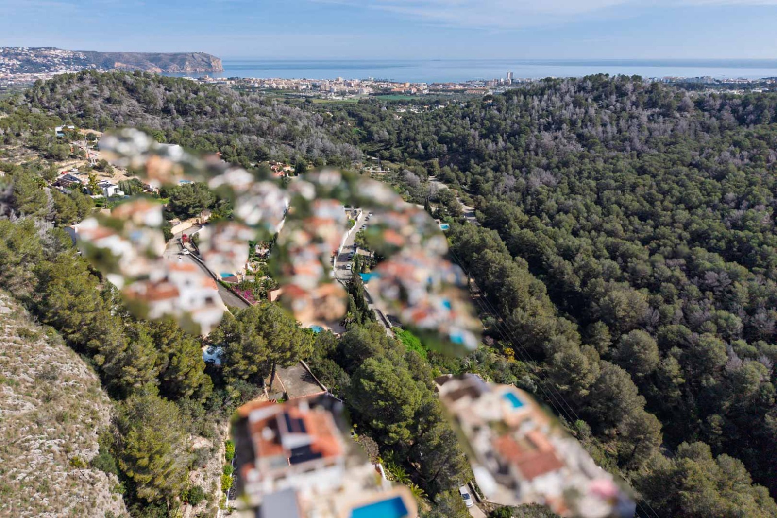 Elevated aerial panorama from the Sol de Este area, showcasing dense pine forests leading toward the Jávea coastline and the Mediterranean Sea.