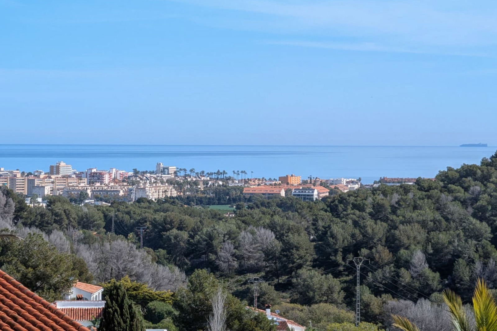 Elevated panoramic views from the plot overlooking the Mediterranean Sea, featuring the coastal skyline of Jávea and lush pine forests.