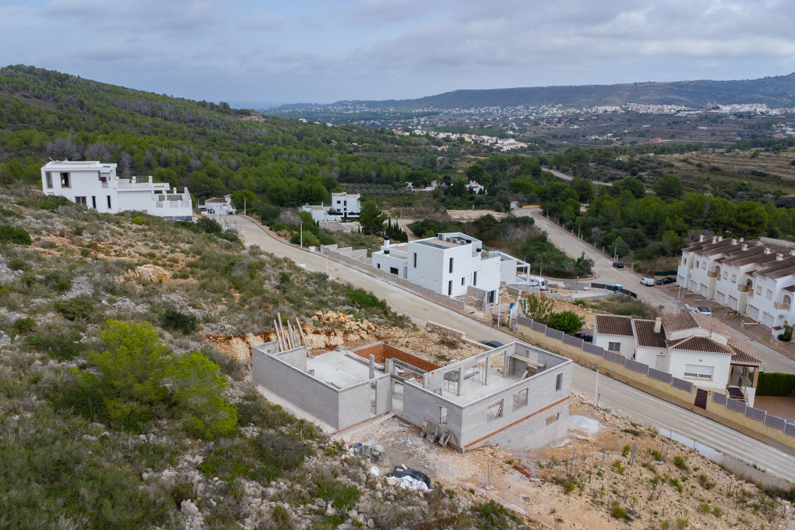 Elevated view of the villa under construction in Pedreguer, showcasing the concrete structure and foundation on a hillside with panoramic valley views.