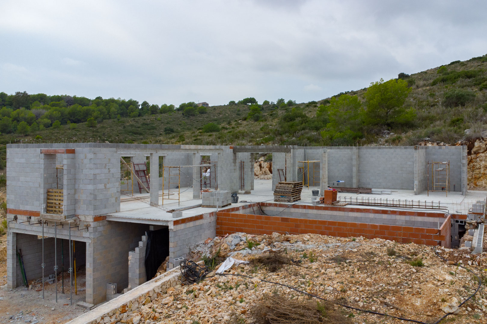 Modern villa under construction in Pedreguer featuring concrete block walls, a dedicated pool structure, and an elevated hillside position.