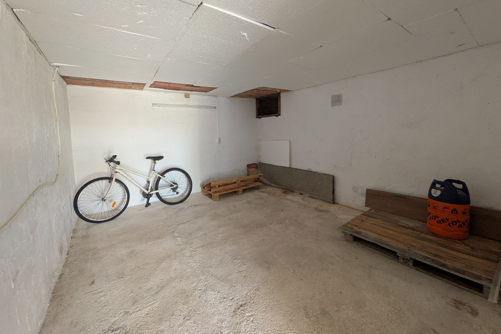Independent storage room featuring paneled ceilings, concrete flooring, and versatile space for bicycles and equipment.