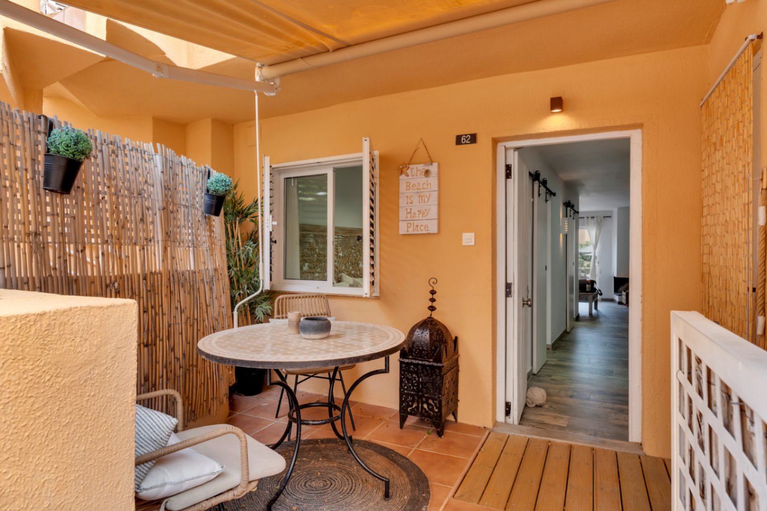 Private terrace with tiled floor, round table with wicker chairs, and bohemian-style decor.