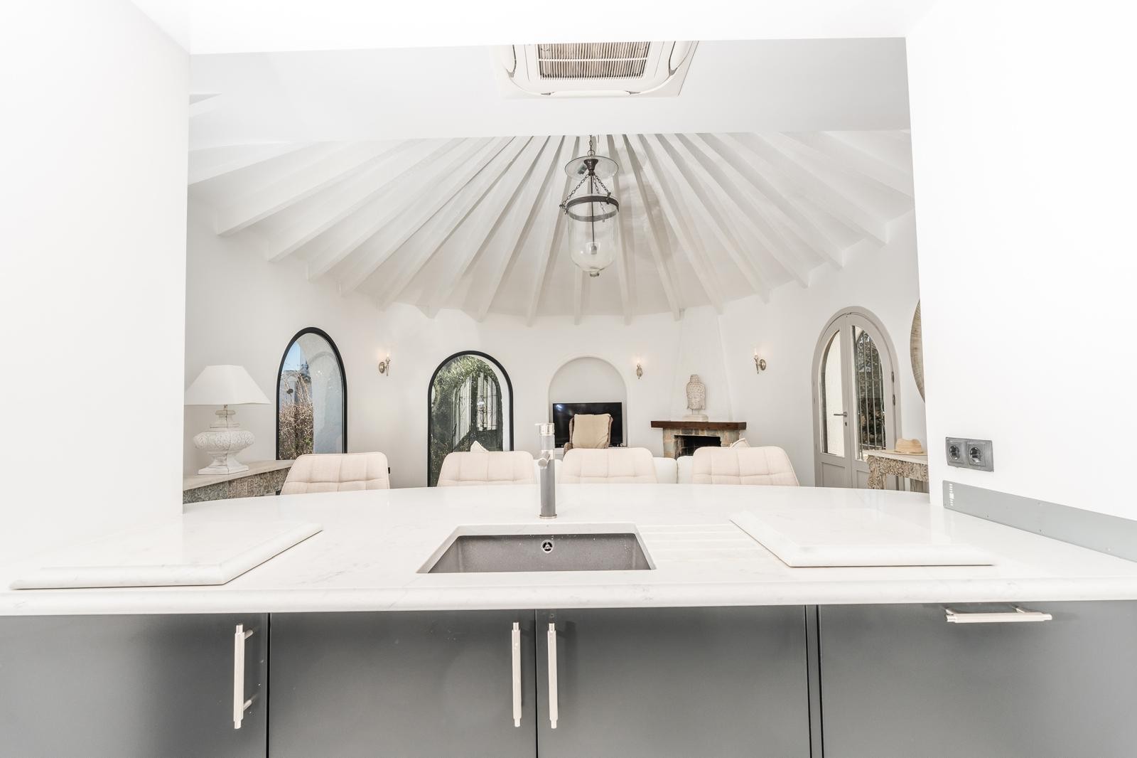 View from the kitchen's marble countertop looking into the circular living room with its distinctive beamed vaulted ceiling and fireplace.