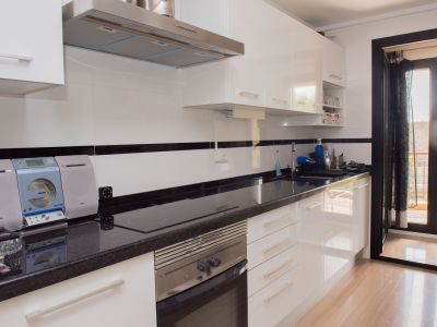 Modern kitchen featuring glossy white cabinets, dark granite countertops, integrated appliances, and direct balcony access.