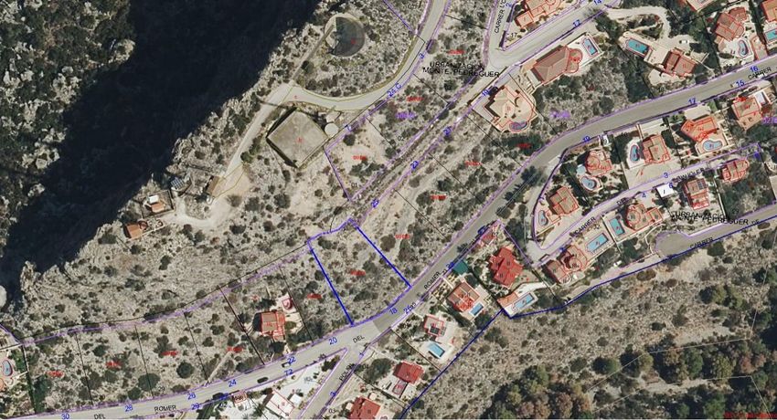 Aerial view of the urban plot, outlined in blue, situated alongside 'ROMER' road within the Monte Pedreguer urbanization. The undeveloped terrain is visible, surrounded by established residential properties.