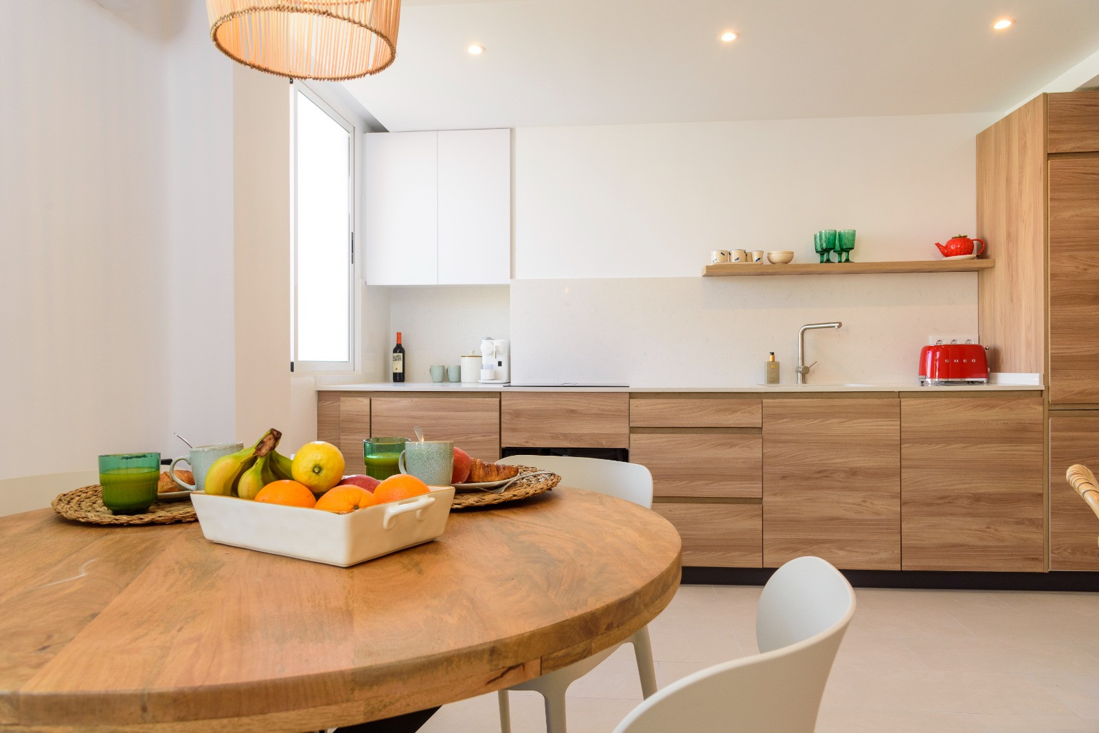 Dining area featuring a circular wooden table and an integrated kitchen with oak-finish cabinetry, white countertops, and recessed ceiling lighting.