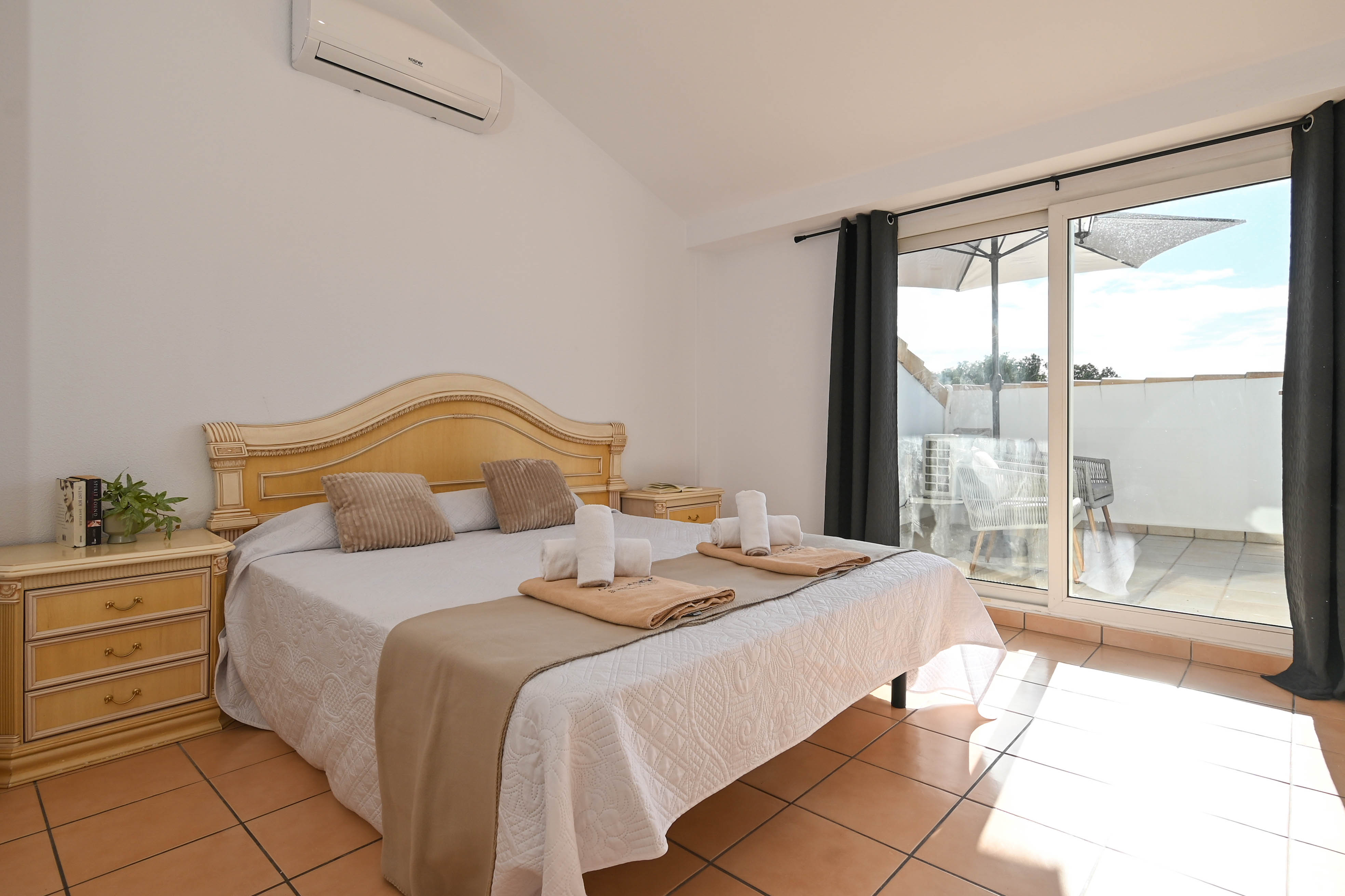 Bedroom featuring vaulted ceilings, air conditioning, and direct terrace access. The space includes terracotta flooring and classic wooden furniture.