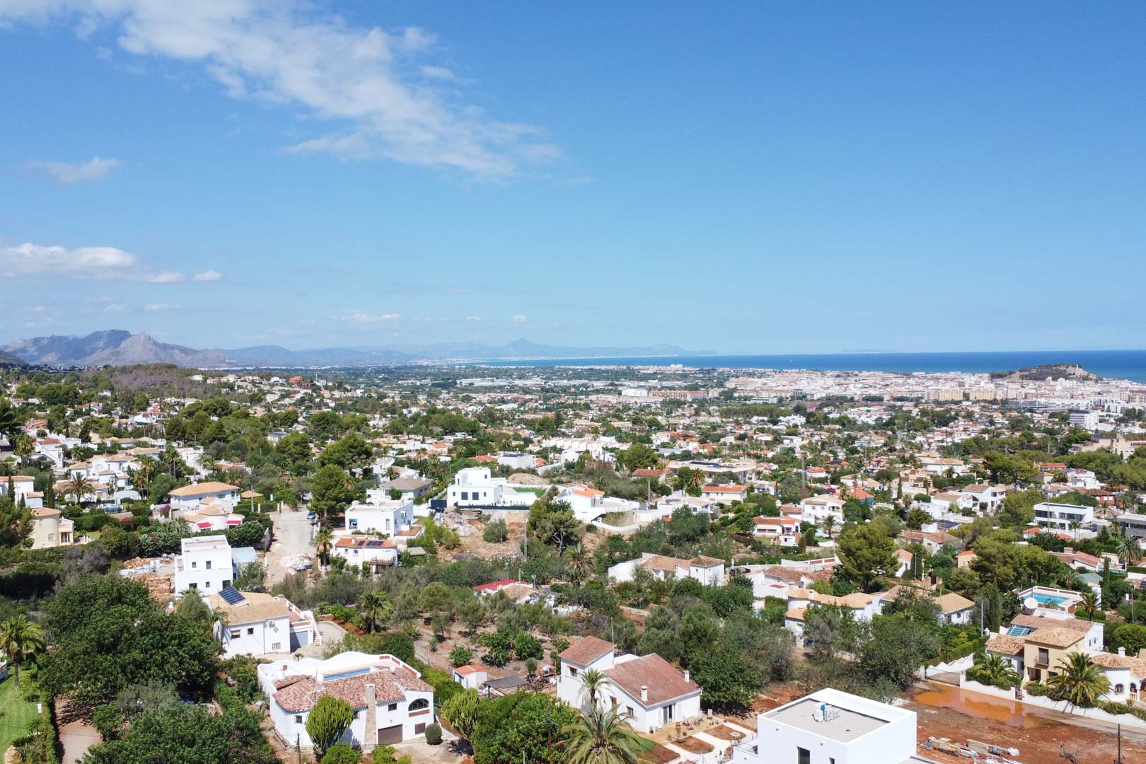 Panoramic aerial view of the residential area in Dénia, showcasing the proximity to the Mediterranean Sea and the established neighborhood of white villas.