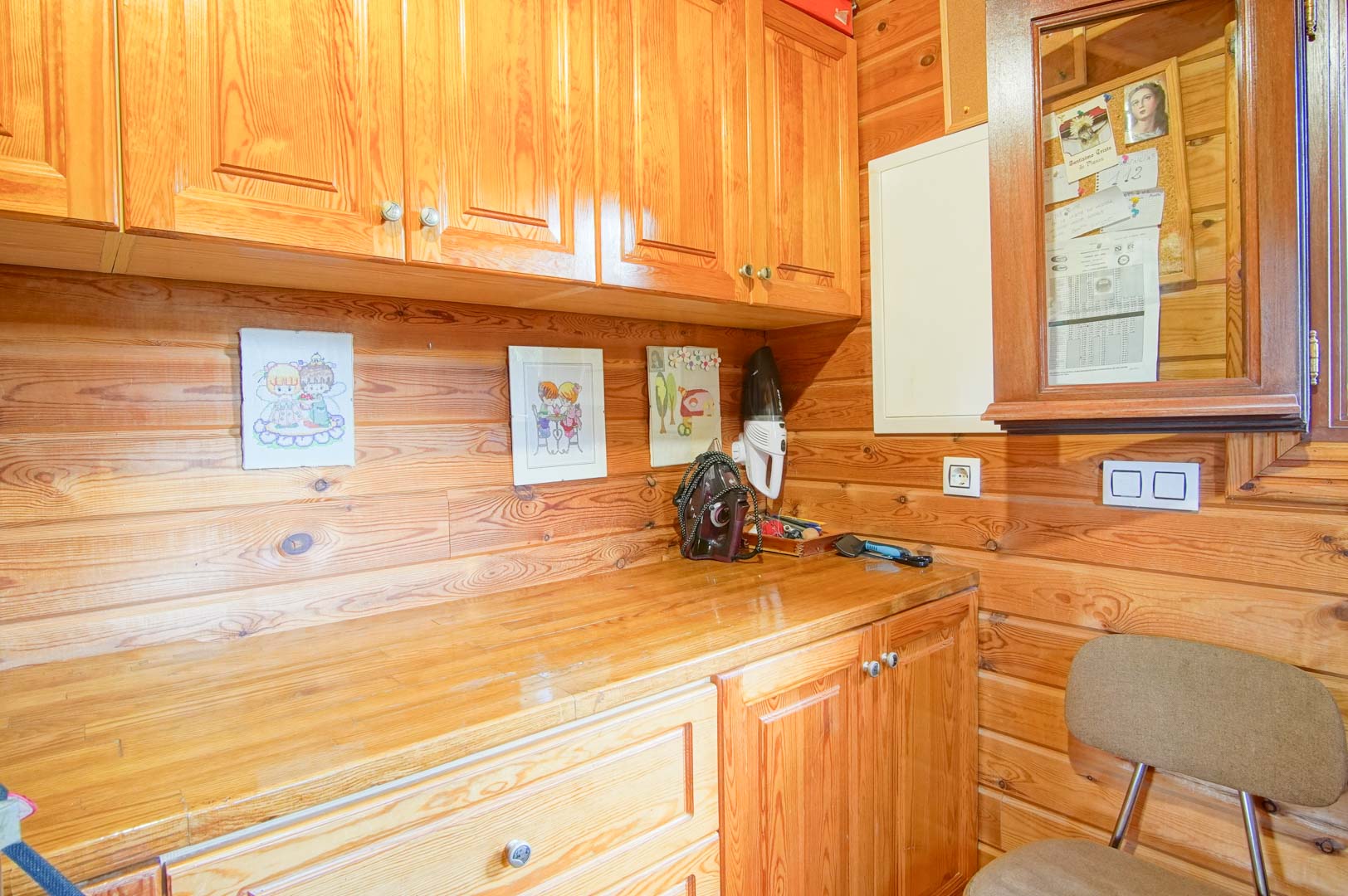 Functional workspace or pantry featuring solid pine wood paneling, matching cabinetry for storage, and a practical wooden countertop in a rustic style.