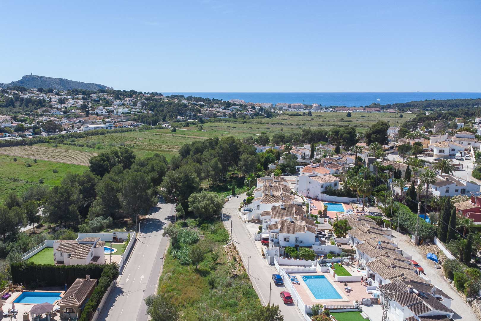 Elevated panoramic view of Moraira showcasing the Mediterranean coastline, integrated green landscapes, and the surrounding residential area with private villas.