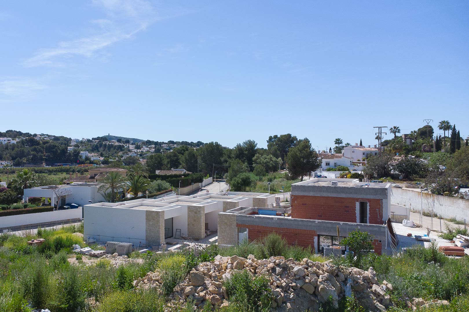 Exterior view of the property under construction, featuring natural stone cladding and modern architectural lines set against the Moraira landscape.