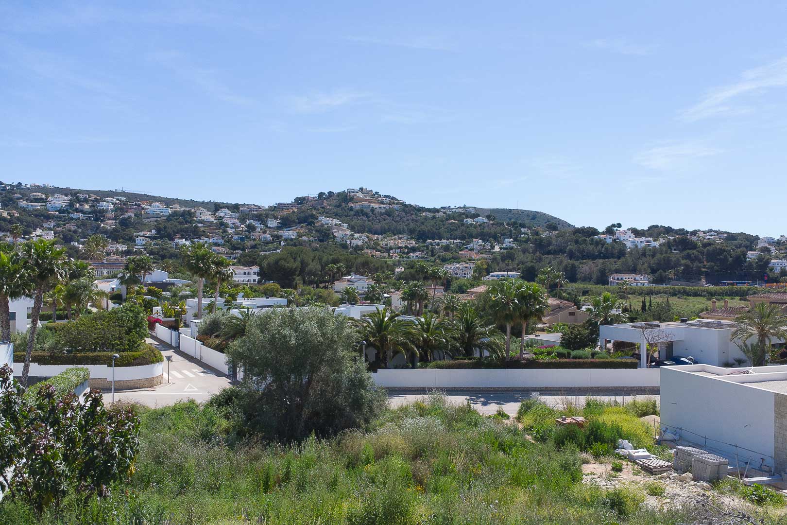 Panoramic views from the property overlooking the Moraira residential landscape, featuring green hills and Mediterranean architecture under a clear sky.