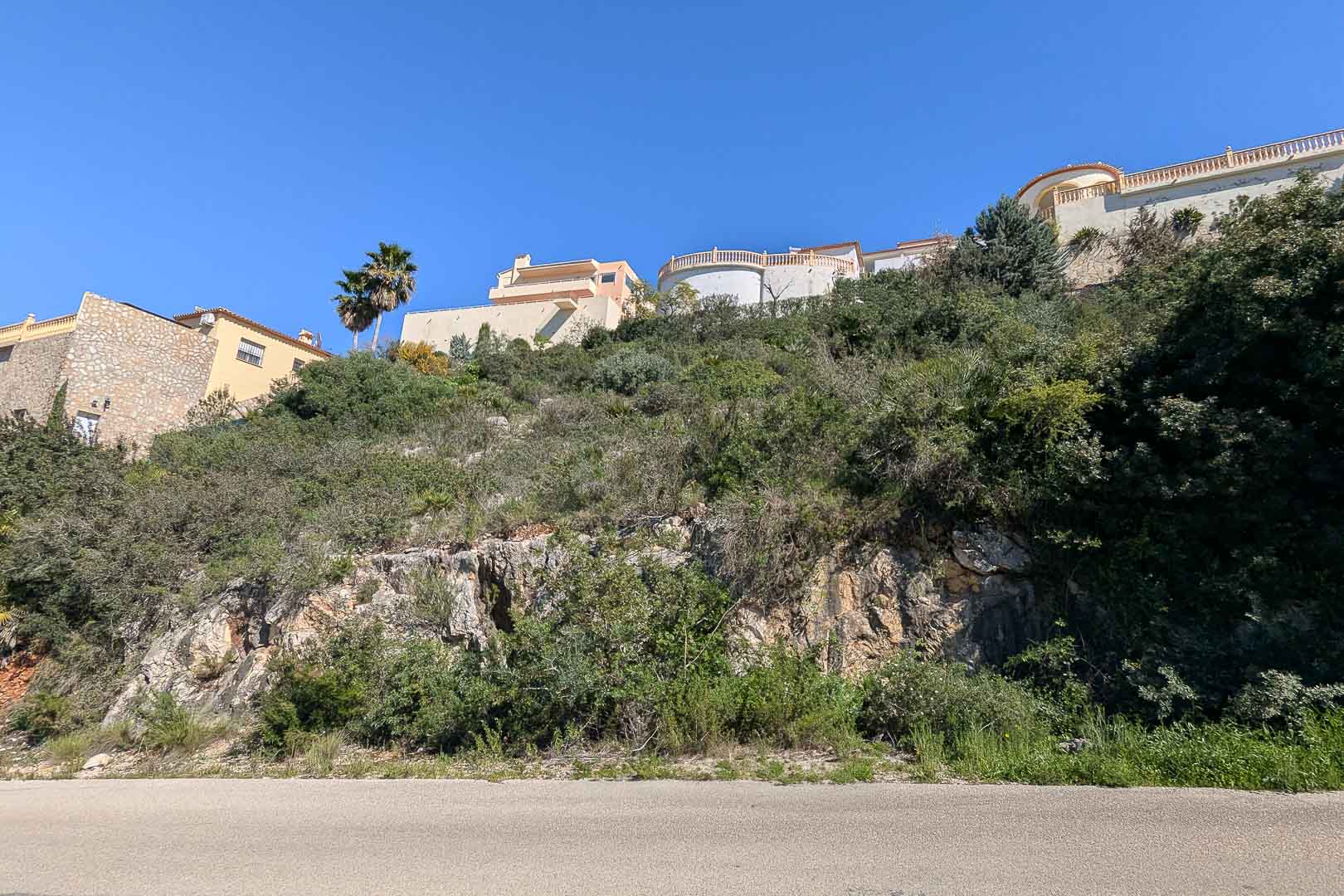 Exterior view of a villa under construction in Pedreguer, Costa Blanca, surrounded by Mediterranean vegetation and natural rocks.