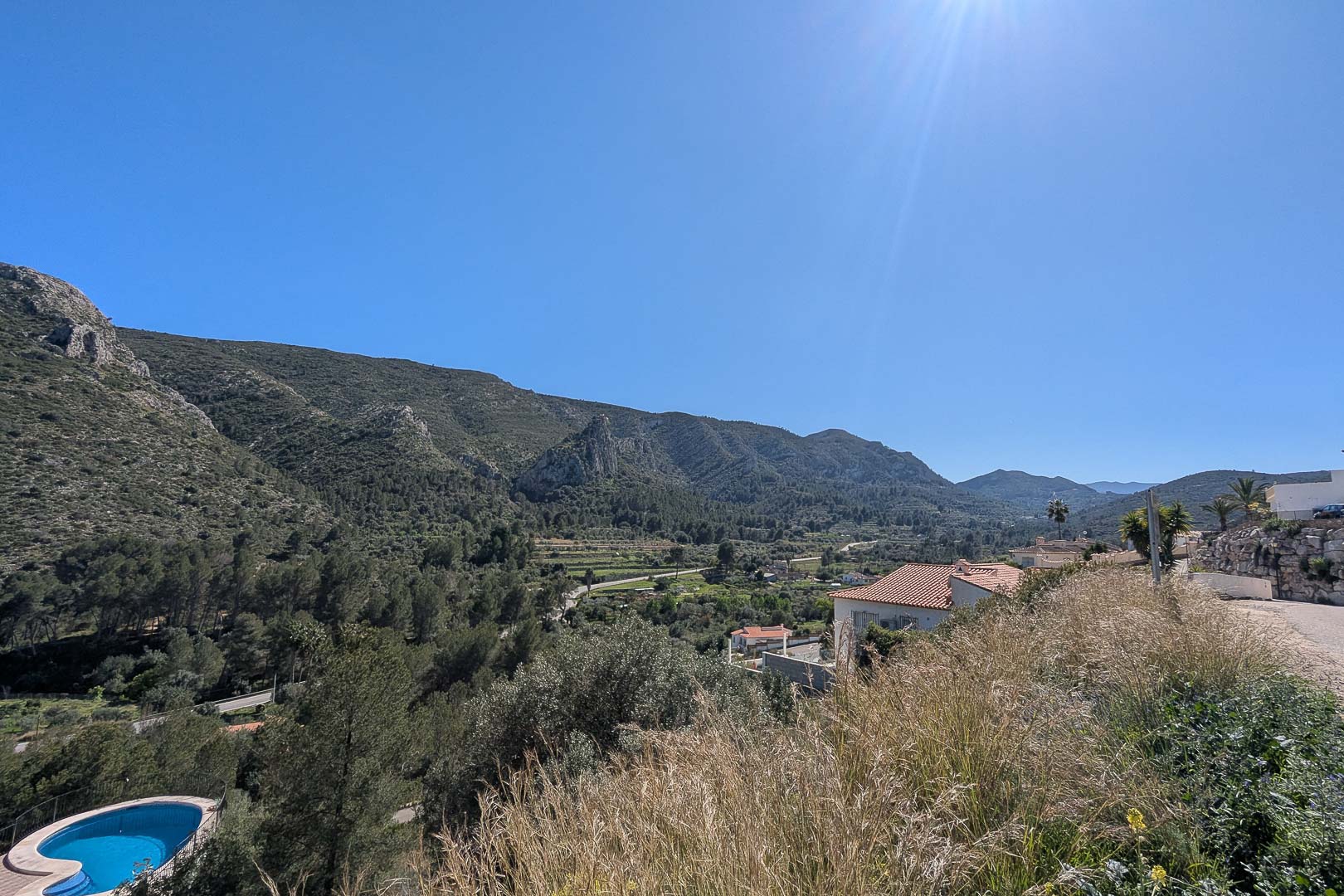 Elevated panoramic views of the Pedreguer valley and surrounding mountains, showcasing the lush Mediterranean landscape and clear blue skies.