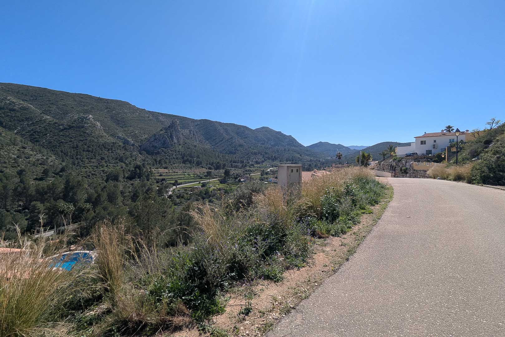 Panoramic views from the property access road overlooking the valley and the surrounding mountains of Pedreguer under a clear sky.