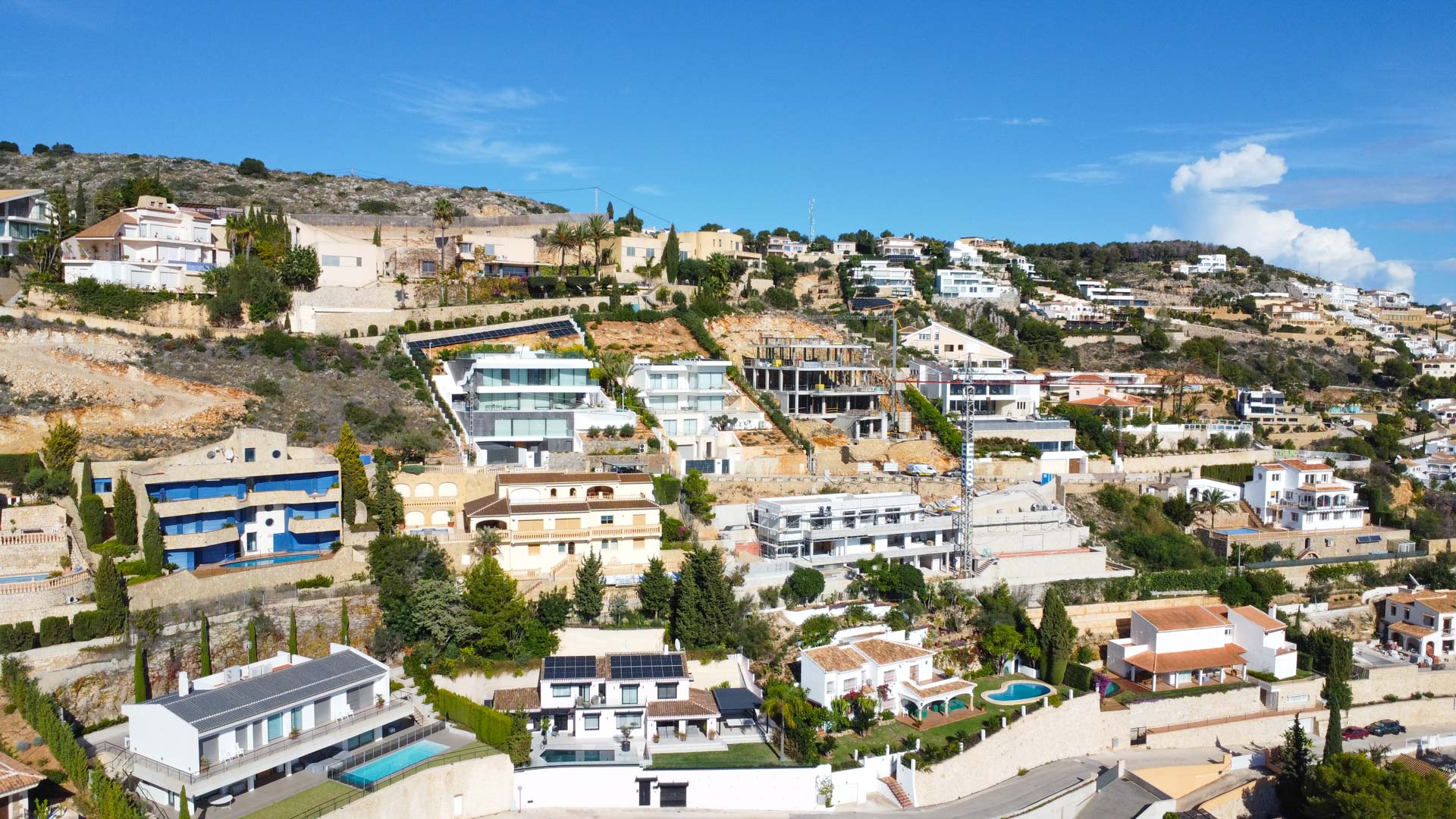 Aerial perspective of the La Corona residential area in Jávea, highlighting the terraced villas built into the hillside with views over the Mediterranean coast.