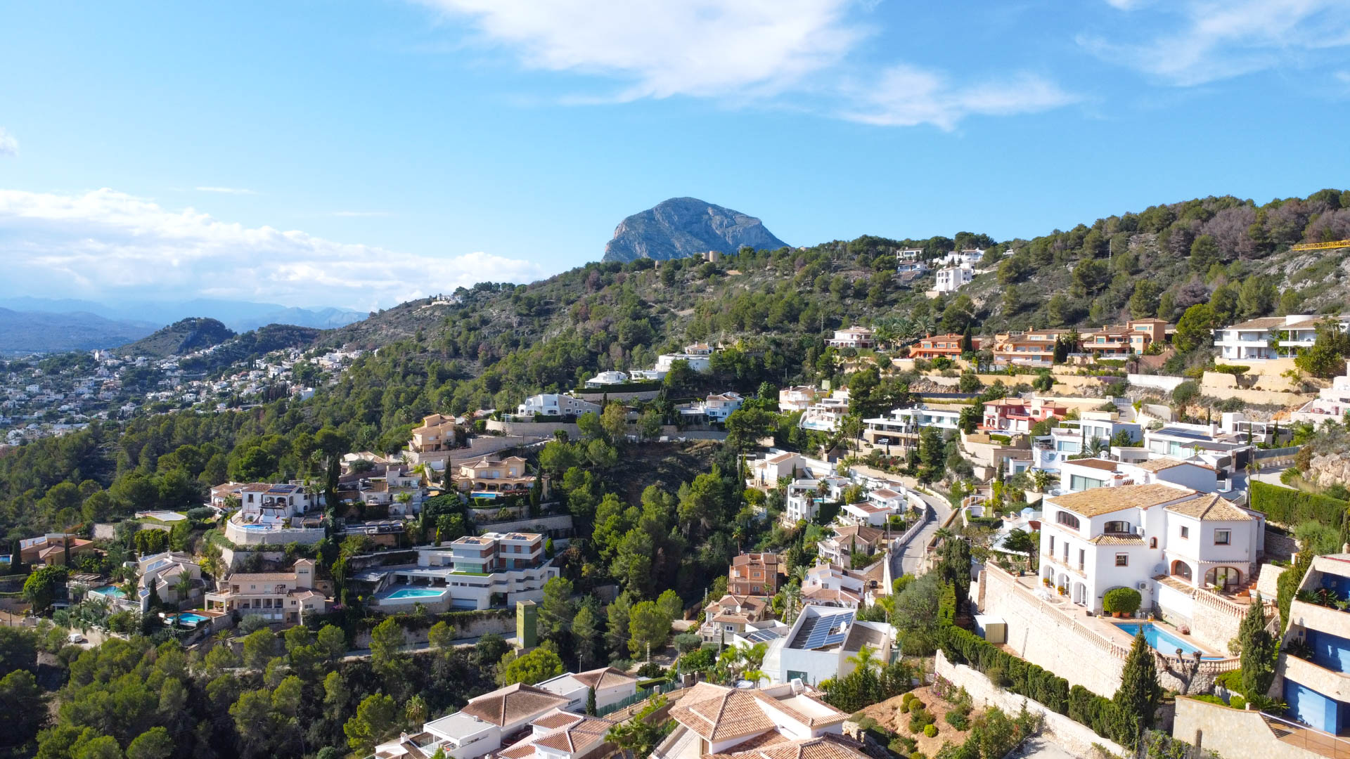 Aerial view of the La Corona residential area in Jávea, showing Mediterranean villas nestled on the hillside with the Montgó mountain in the background.