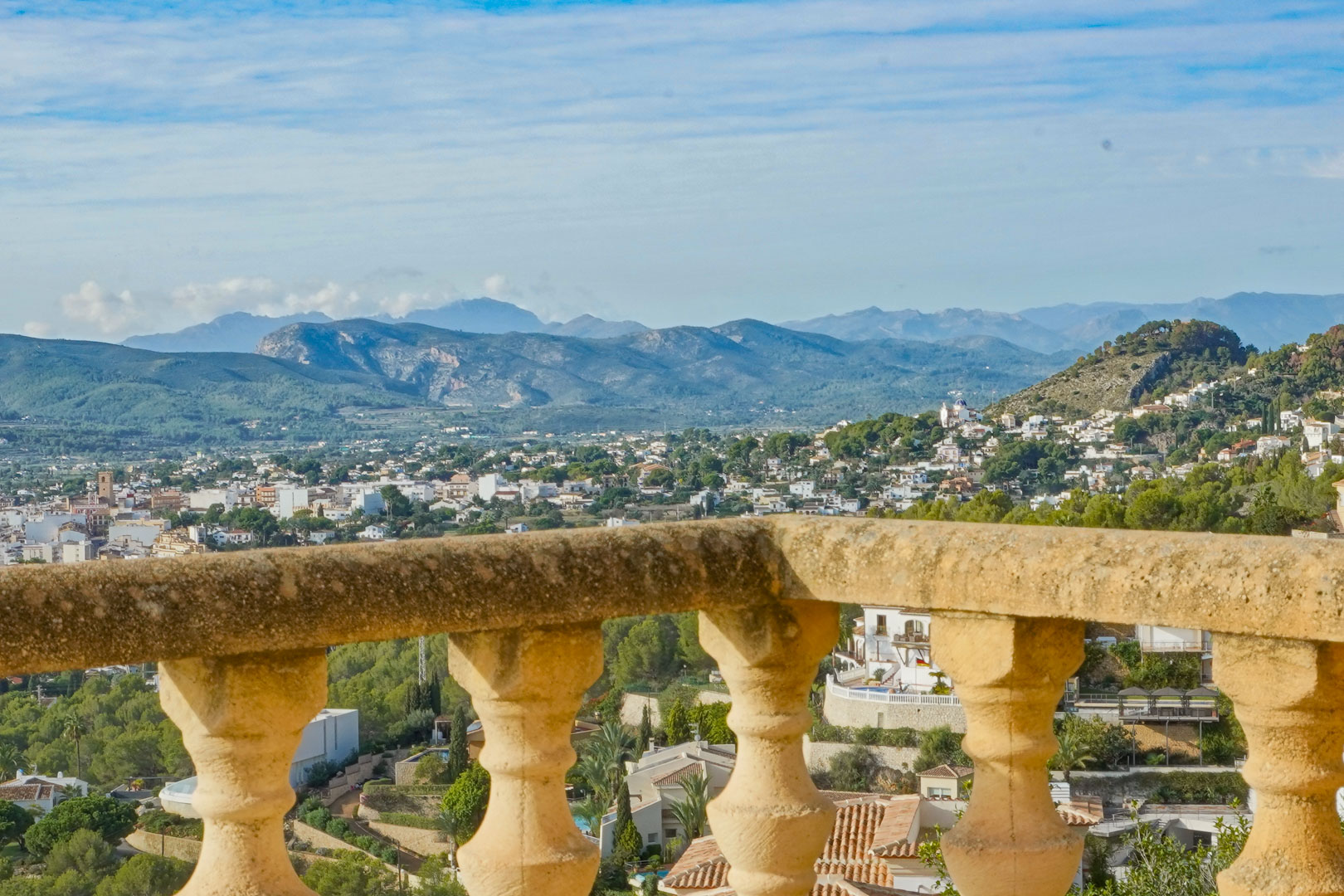 Panoramic view from the terrace featuring traditional stone balusters, overlooking the Jávea valley and surrounding mountain ranges.