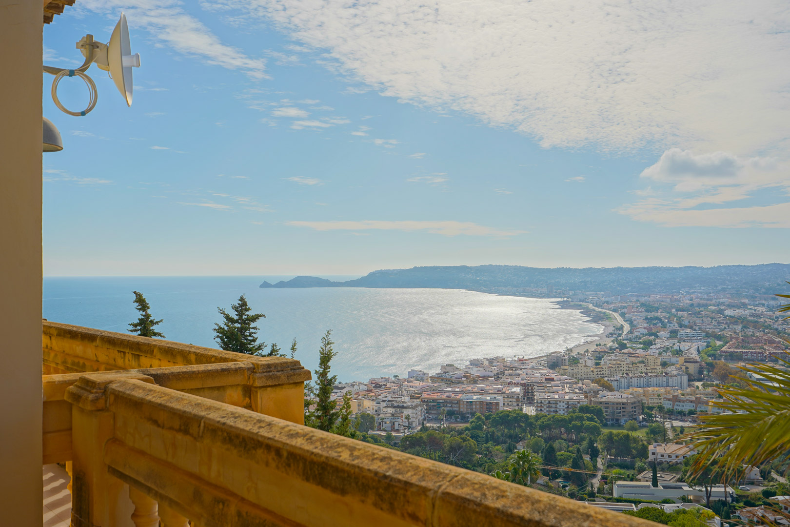 Panoramic view from the upper terrace overlooking Jávea Bay and Cap Negre, featuring a traditional stone balustrade and expansive coastal scenery.