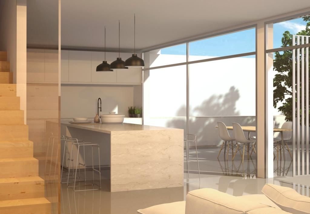 Open-plan kitchen featuring a stone-finish island, black pendant lights, and large glass doors leading to a bright terrace with an outdoor dining area.