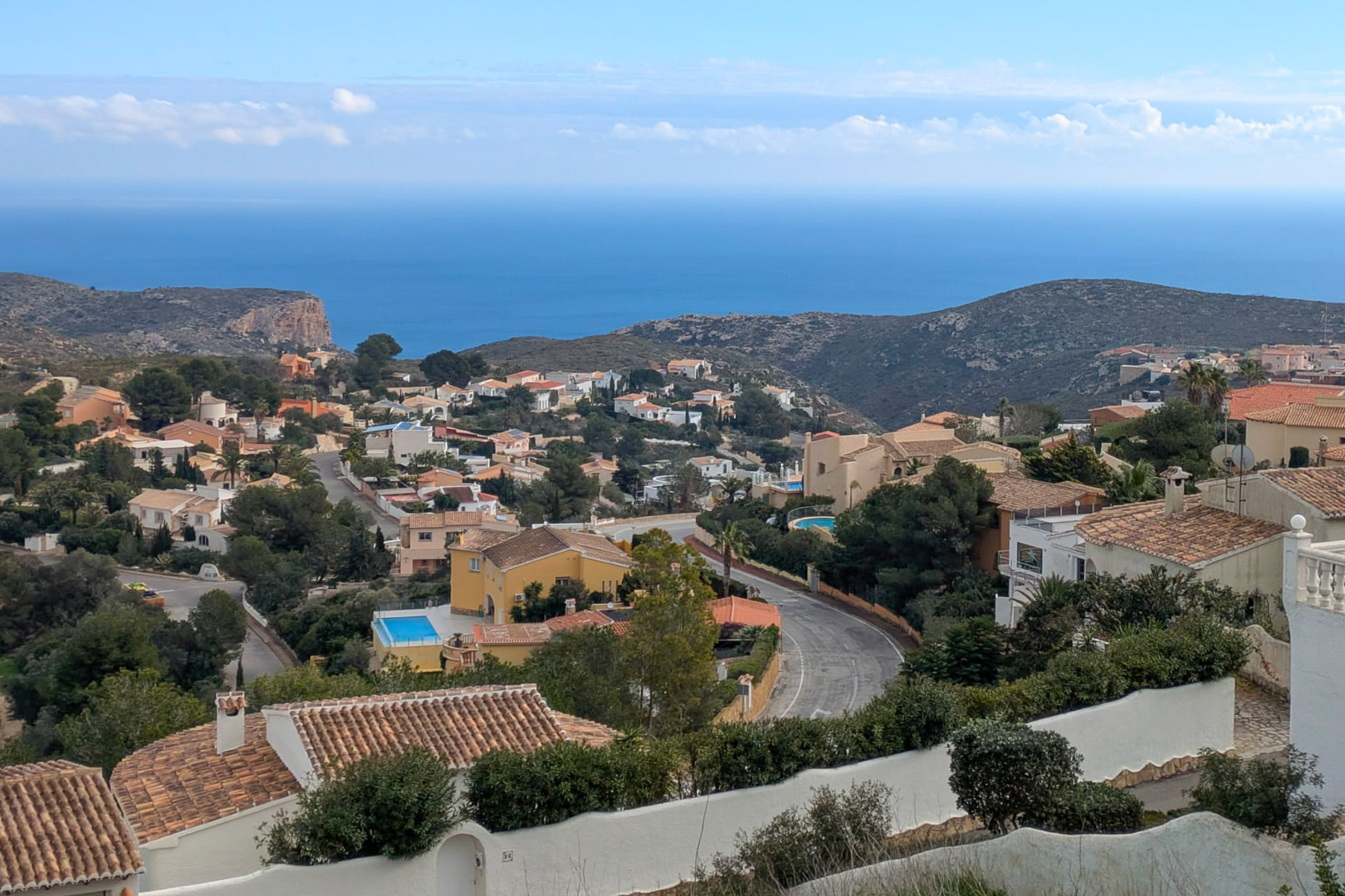 Panoramic views from Cumbre del Sol overlooking the Mediterranean Sea, featuring the established residential area and the rugged coastline of the Costa Blanca.