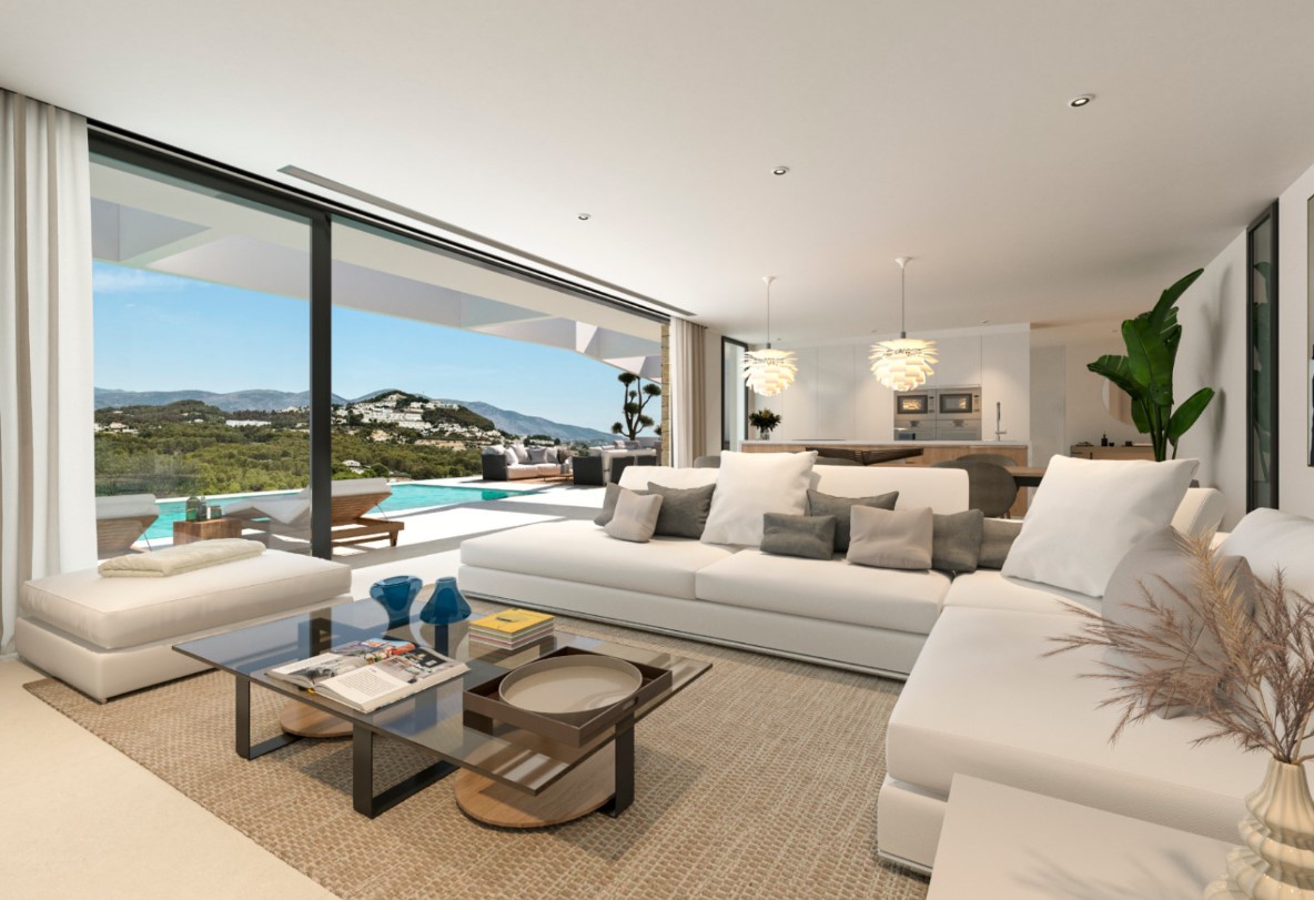 Open-plan living space with a white sectional sofa and glass coffee table, offering direct access to the pool terrace and panoramic mountain views.
