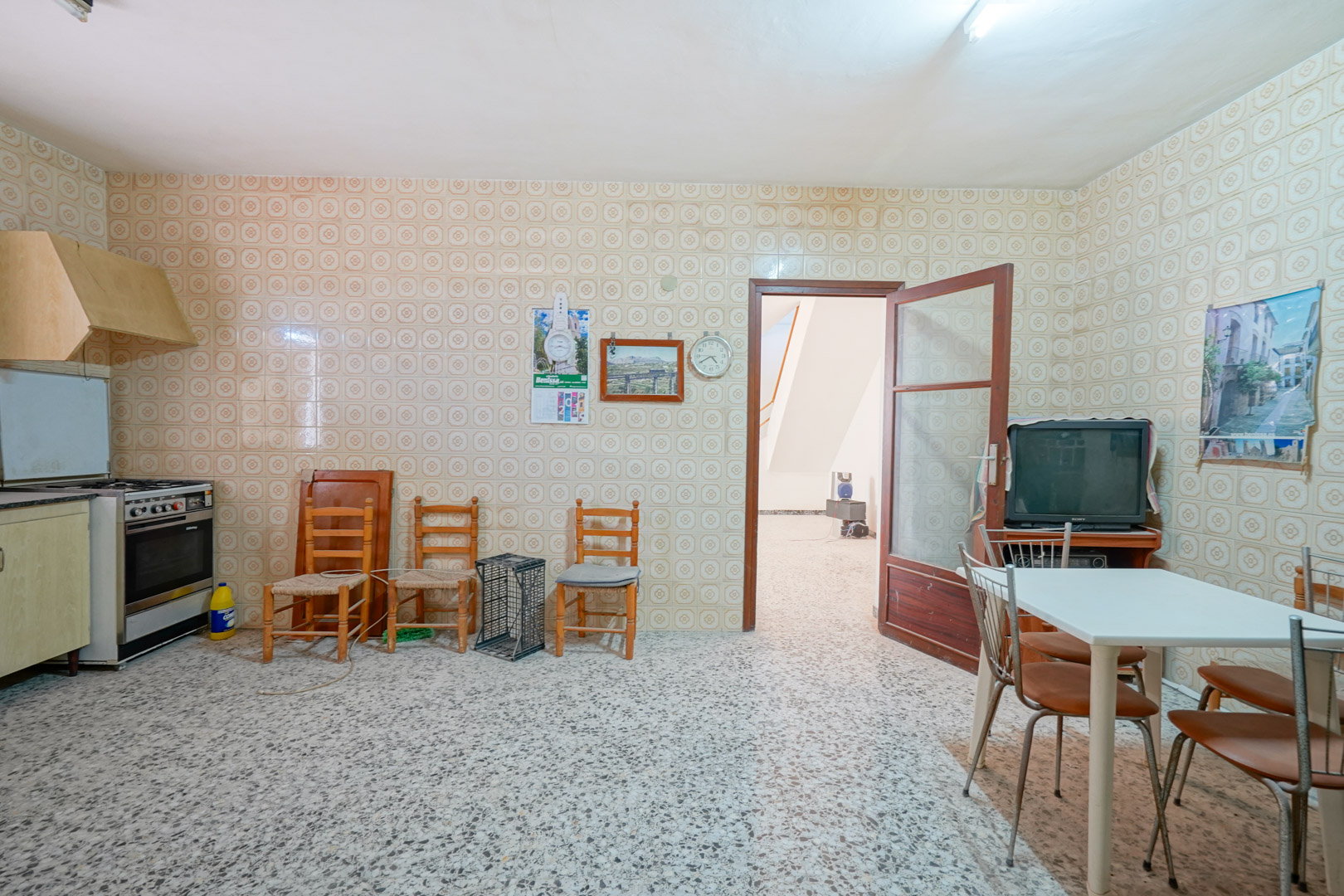 Traditional kitchen featuring vintage patterned wall tiles, terrazzo flooring, and a dining area with direct access to the main hallway.