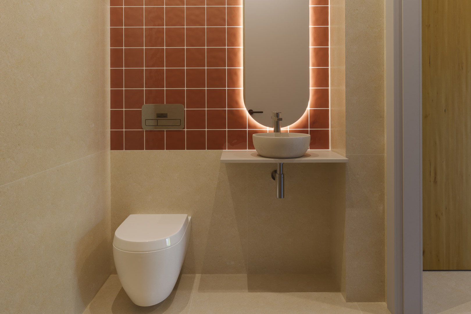 Modern guest toilet featuring terracotta wall tiles, a wall-hung toilet, and a minimalist vessel sink with an oval backlit mirror for ambient lighting.
