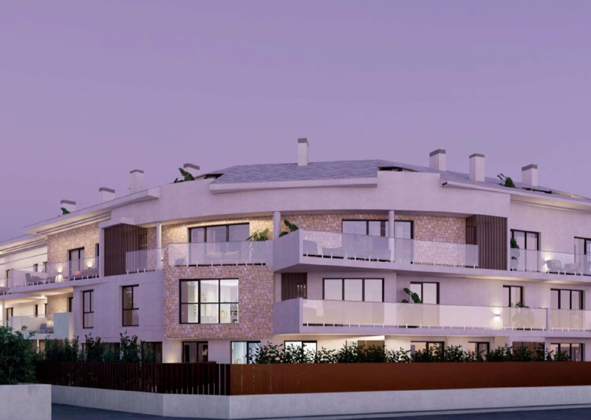 Exterior facade of the residential complex in Javea, featuring natural stone cladding, spacious terraces with glass railings, and integrated lighting at dusk.