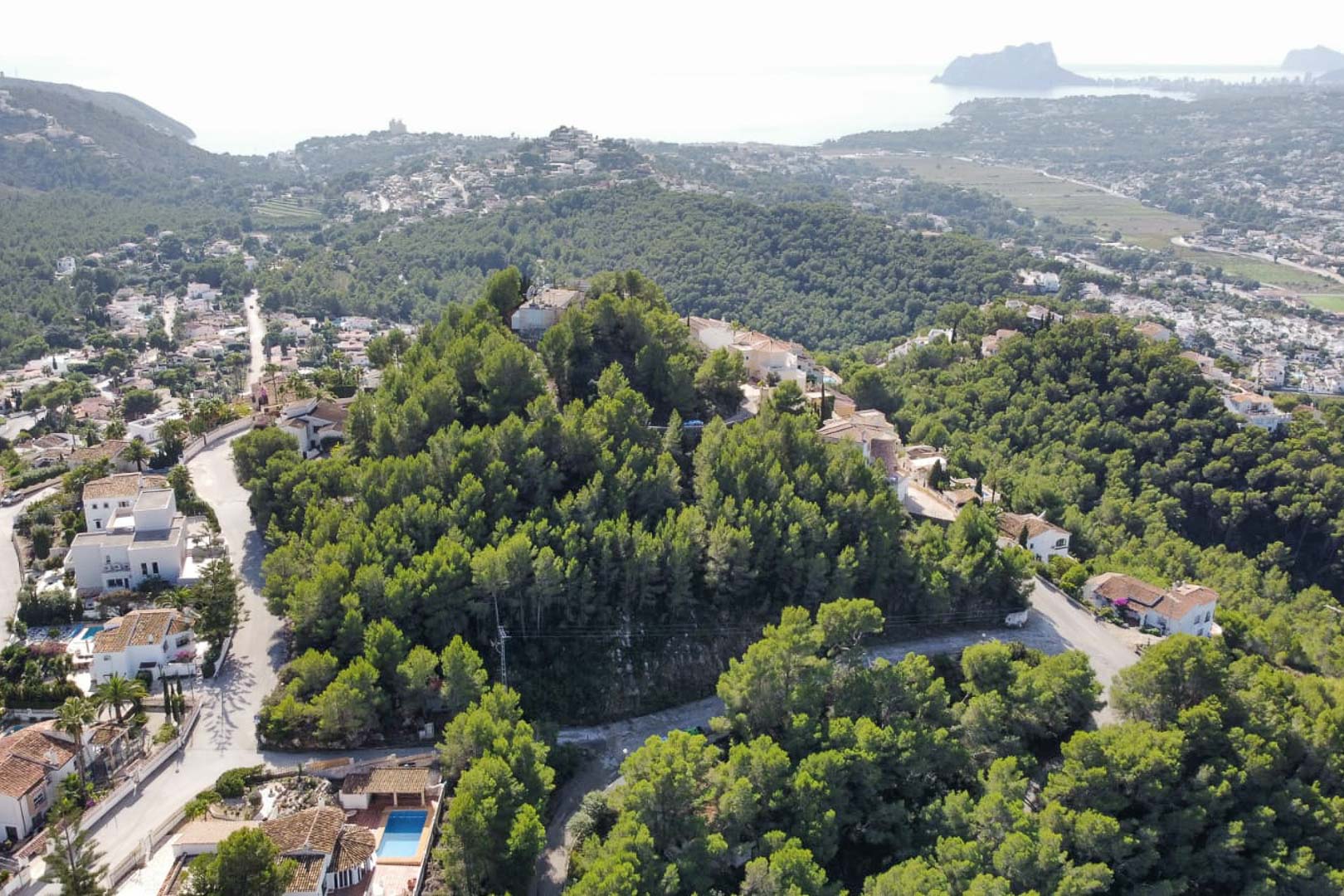 Aerial perspective of the pine-covered hillside in Paichi, showing the plot's elevated position with views of the Peñón de Ifach and the coast.