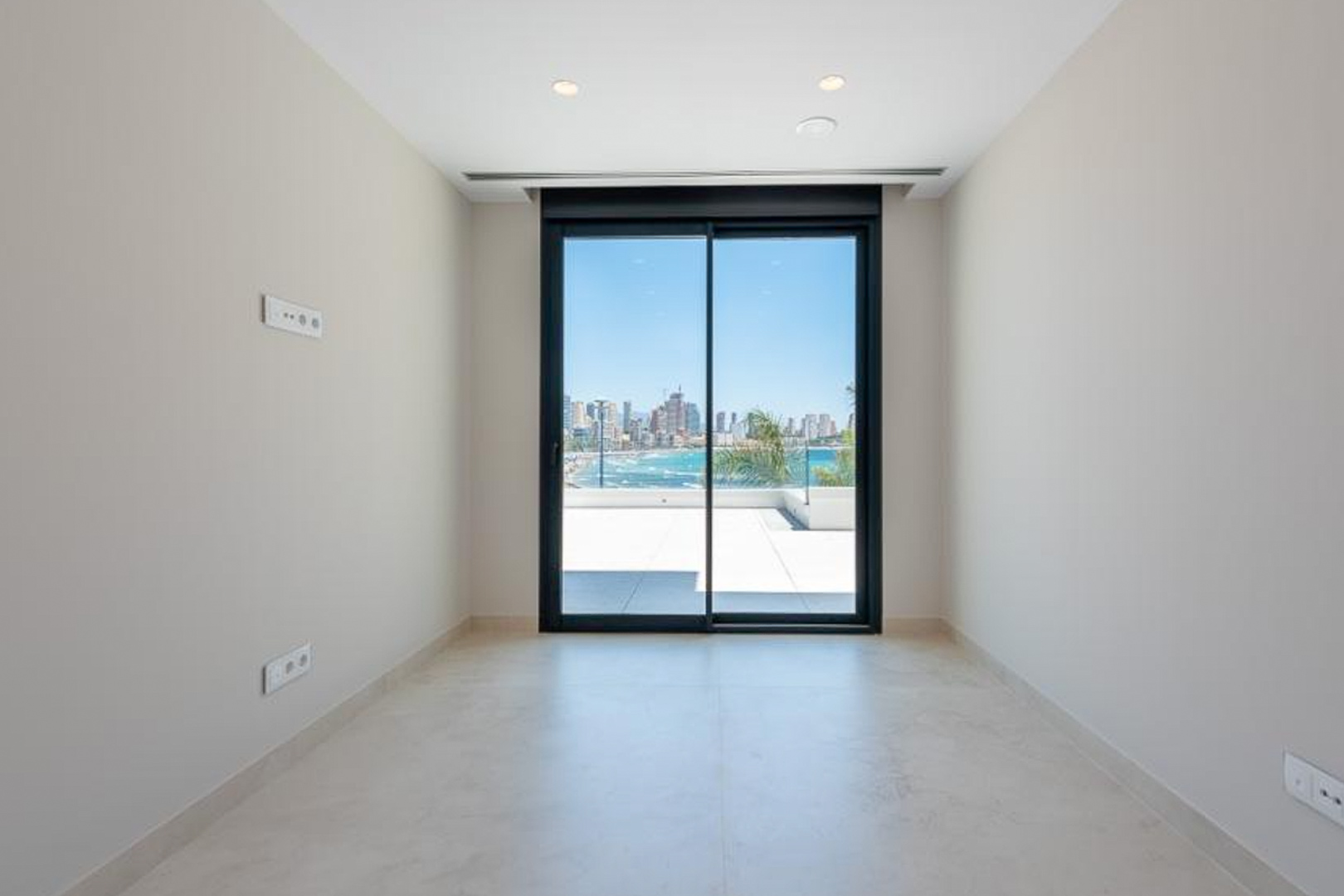 Bright room featuring porcelain flooring, recessed lighting, and large sliding glass doors opening to a terrace with views of the Mediterranean Sea and Benidorm skyline.