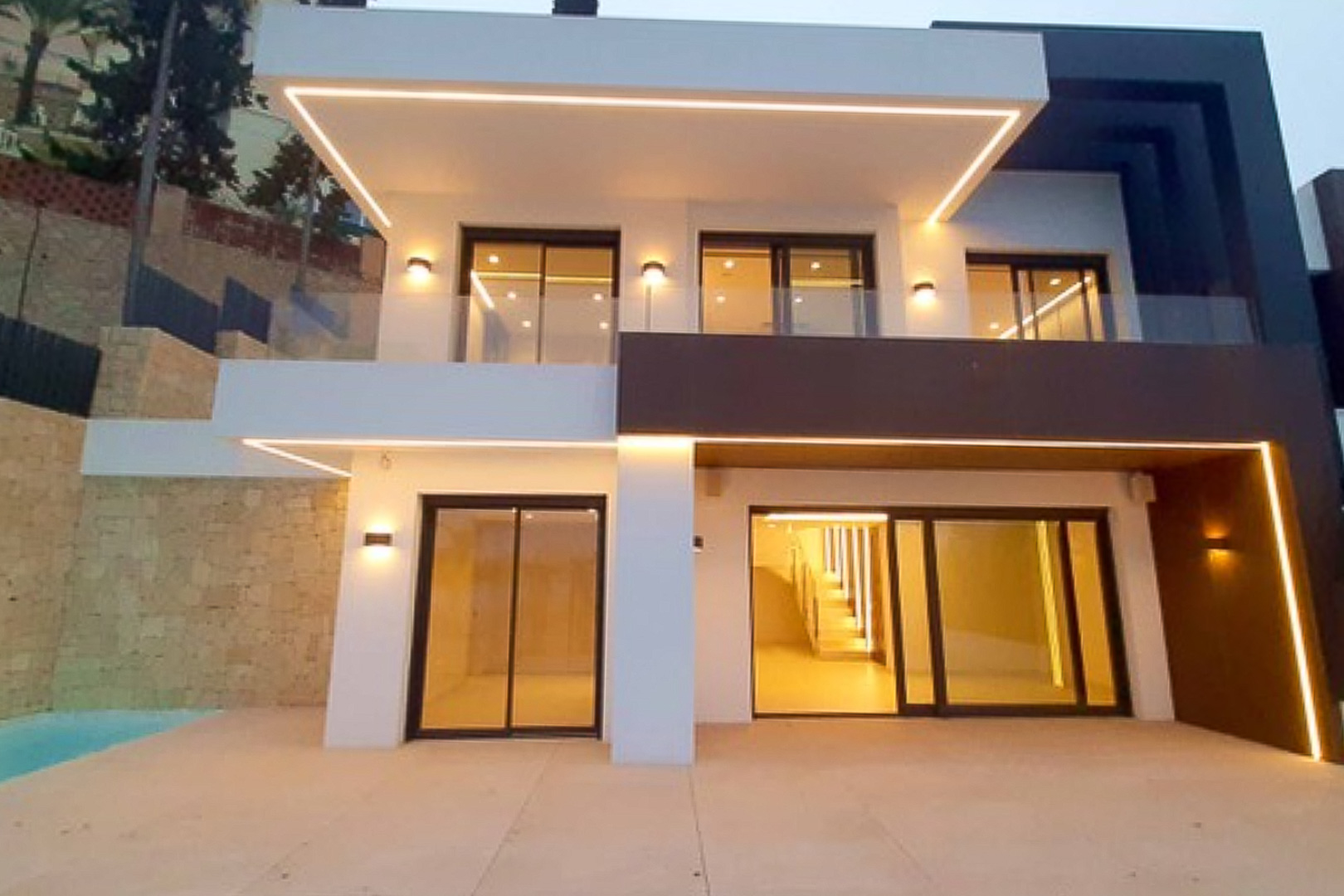Modern facade featuring integrated LED perimeter lighting, large sliding glass doors, and glass-railed terraces showcasing a contrast between white and dark volumes.