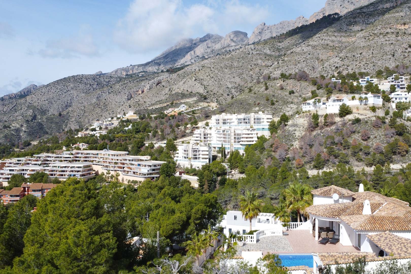 Aerial perspective of the Mediterranean villa and pool area, showcasing its scenic position at the base of the Sierra de Bernia mountain range.