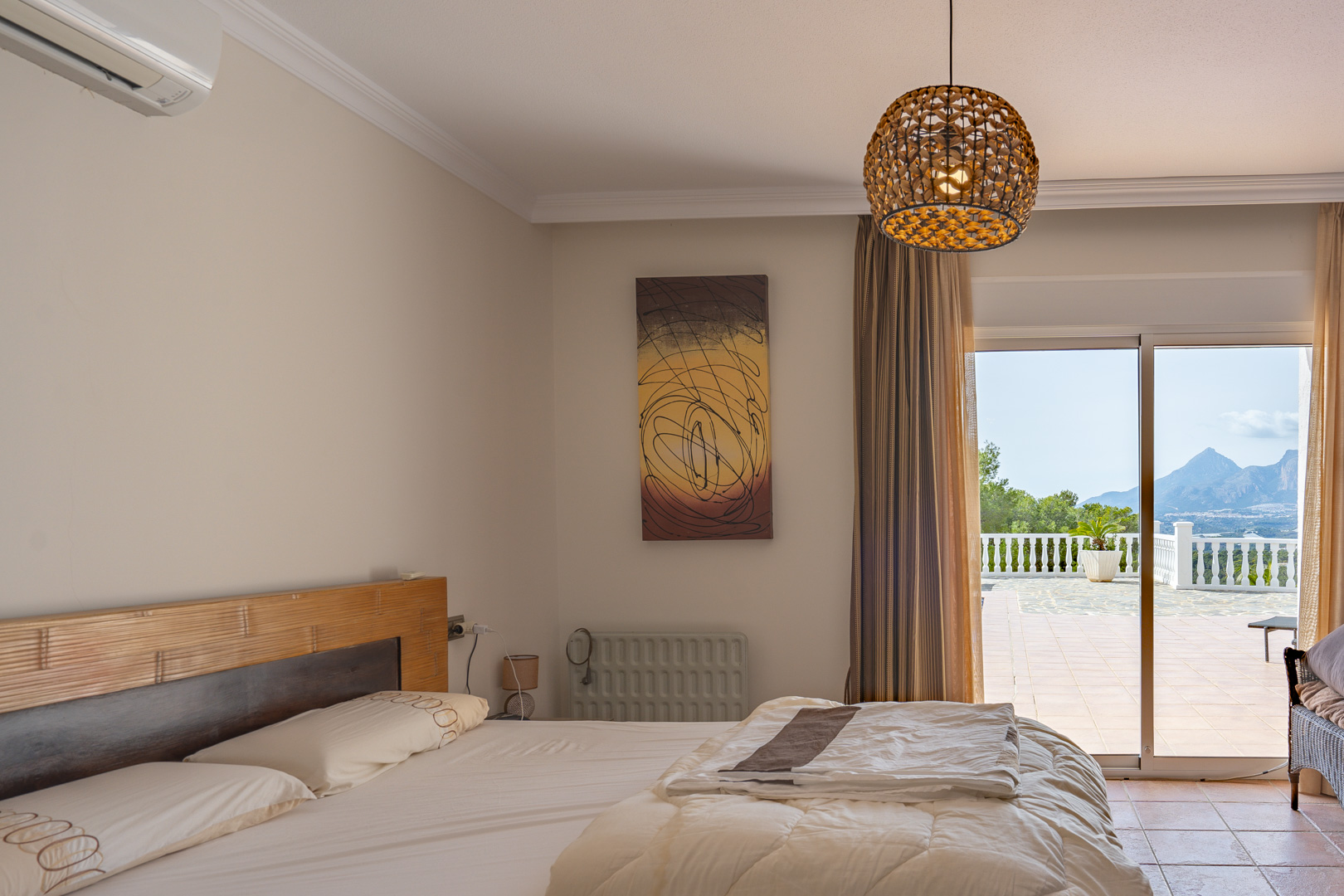 Bedroom featuring a wooden headboard and air conditioning, with sliding doors opening to a terrace overlooking the mountain landscape.