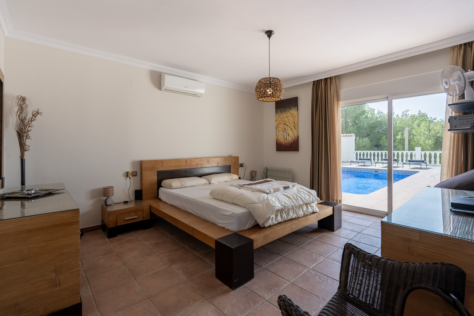 Master bedroom featuring terracotta flooring, air conditioning, and direct access to the private pool terrace through large sliding glass doors.