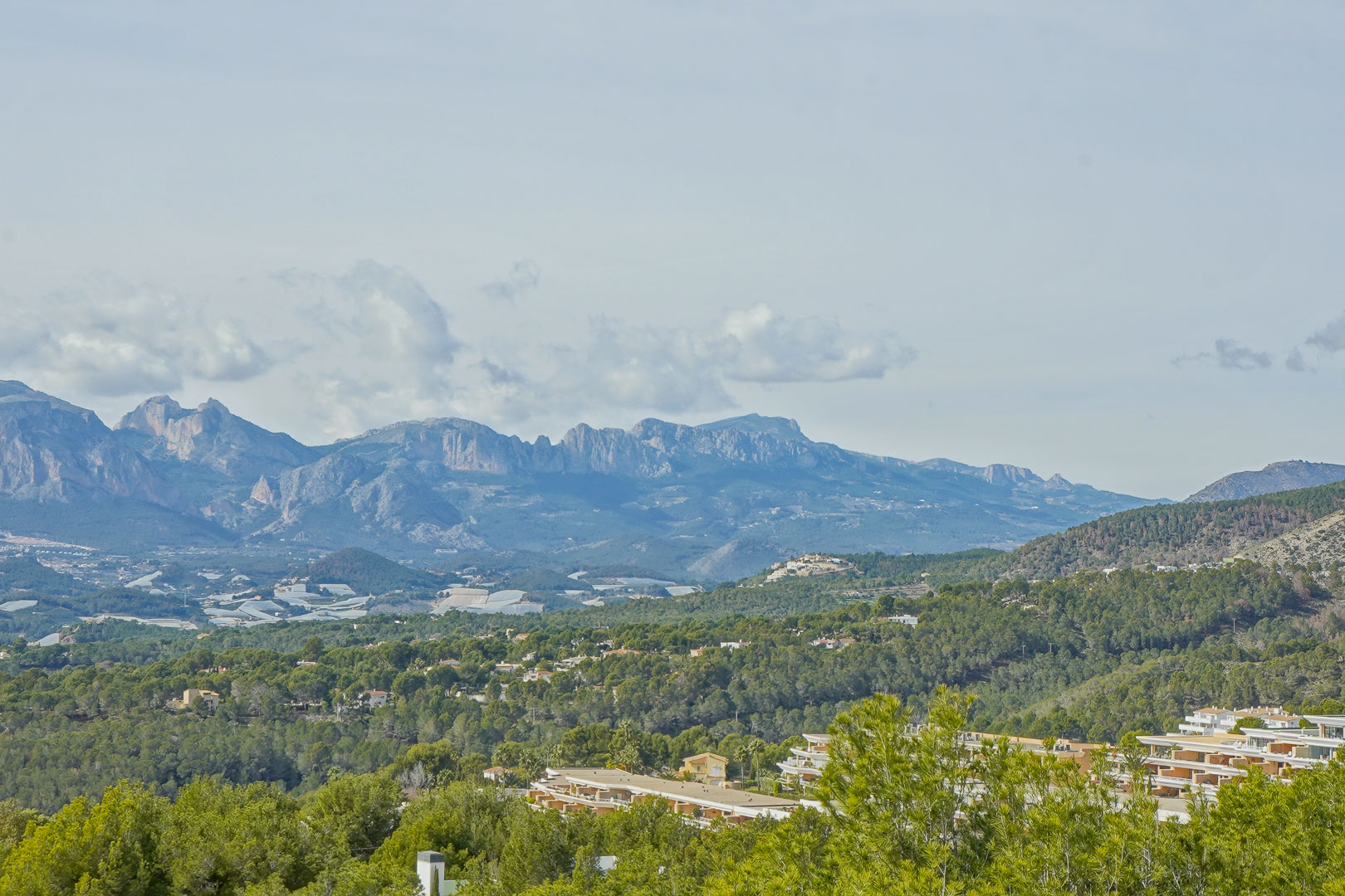 Panoramic views of the Marina Baixa mountain range, featuring the peaks of Sierra Aitana across a lush pine-covered valley.