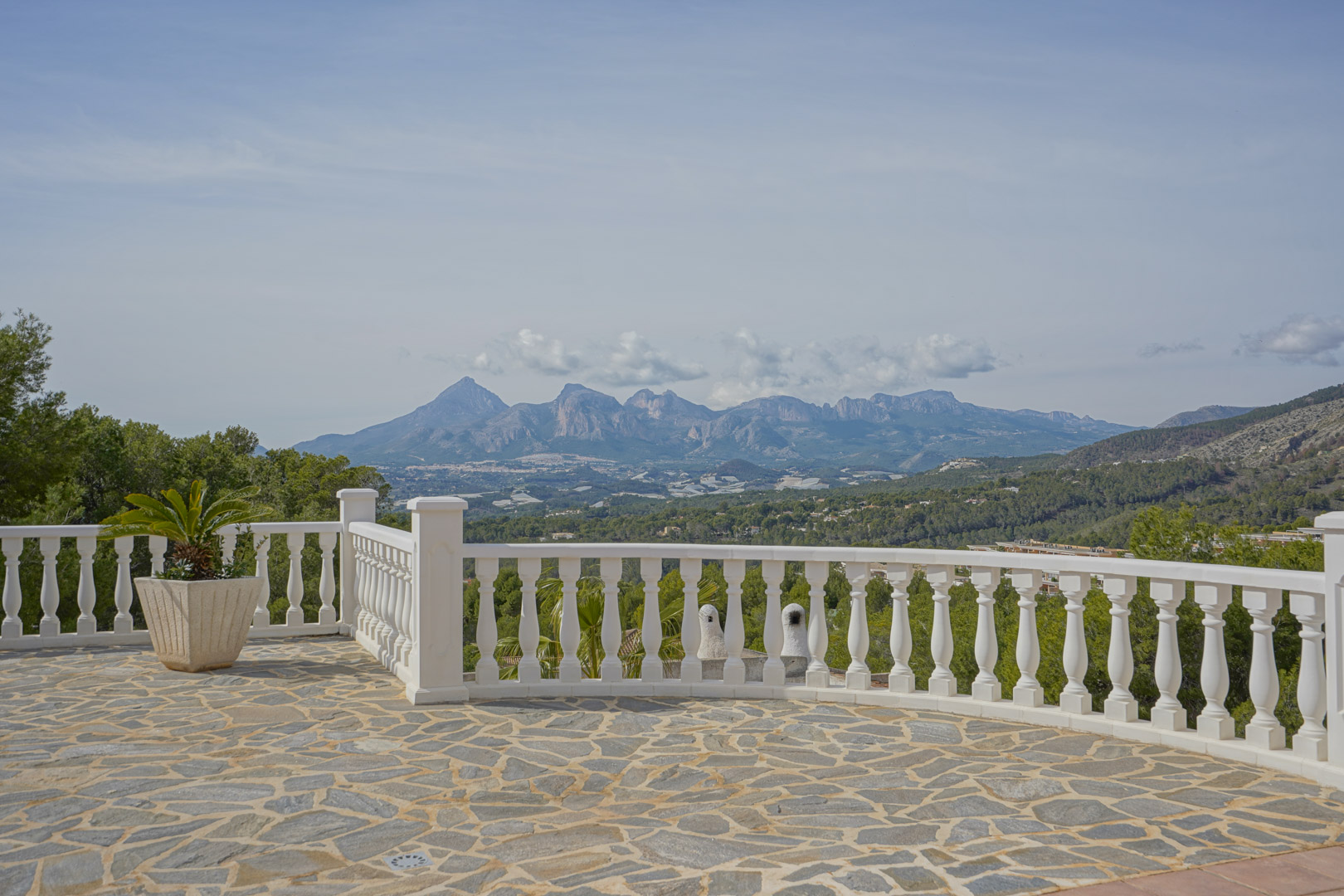 Stone-paved terrace with a classic white balustrade overlooking the Puig Campana and Sierra Aitana mountain ranges.