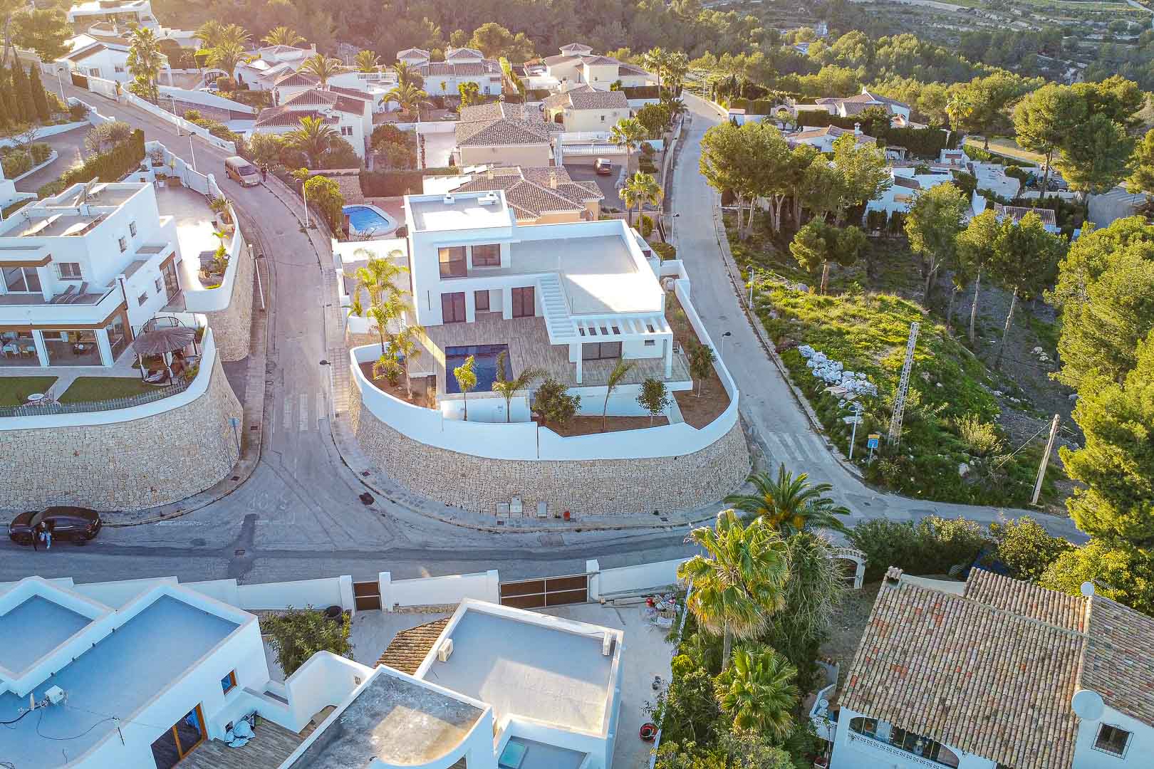 Aerial view of a modern villa with a pool, surrounded by a stone wall and gardens in Benimeit, Moraira.