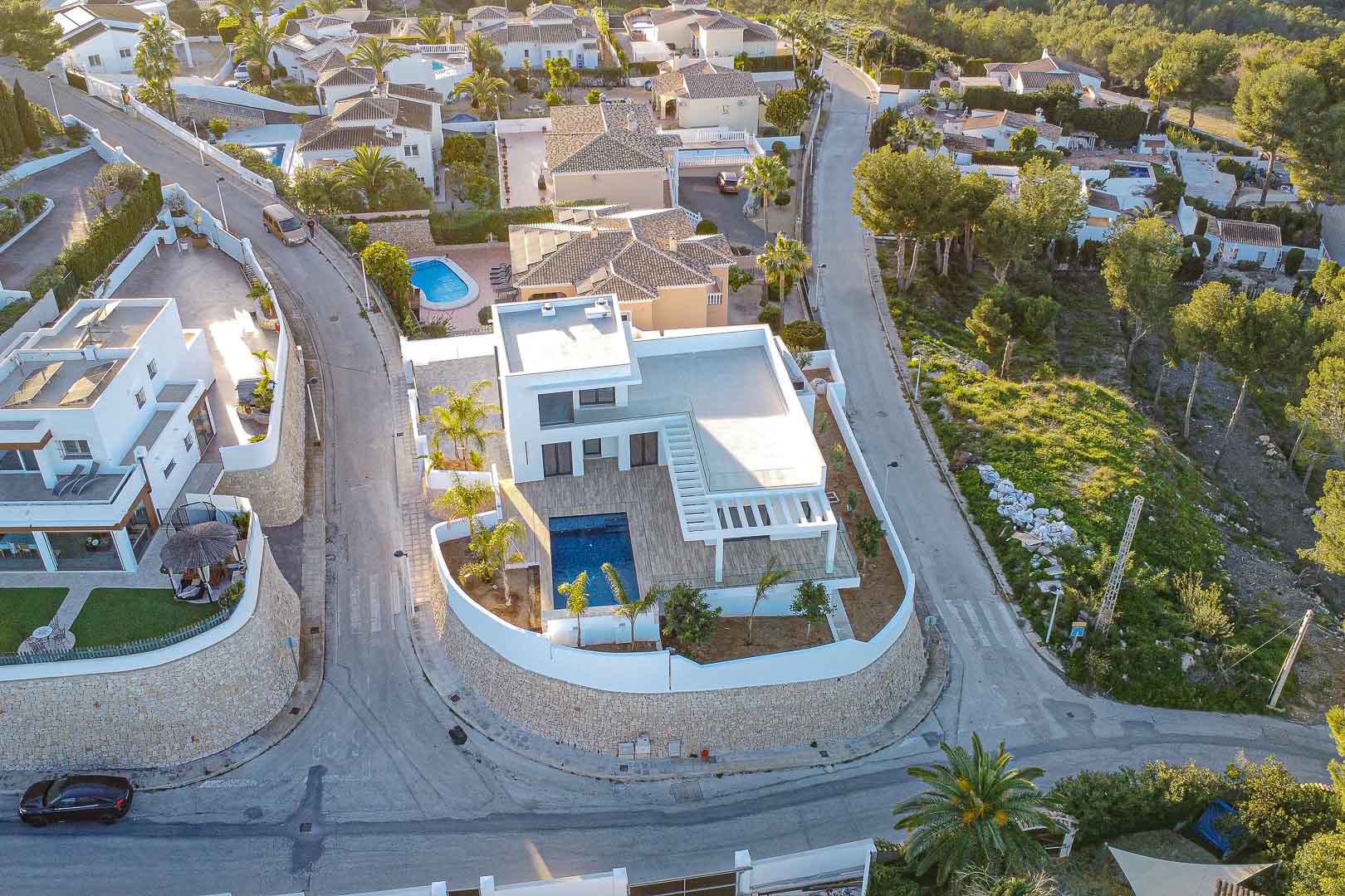 Aerial view of a modern villa with pool in Benimeit, Moraira. Minimalist design, terraces, and Mediterranean garden.