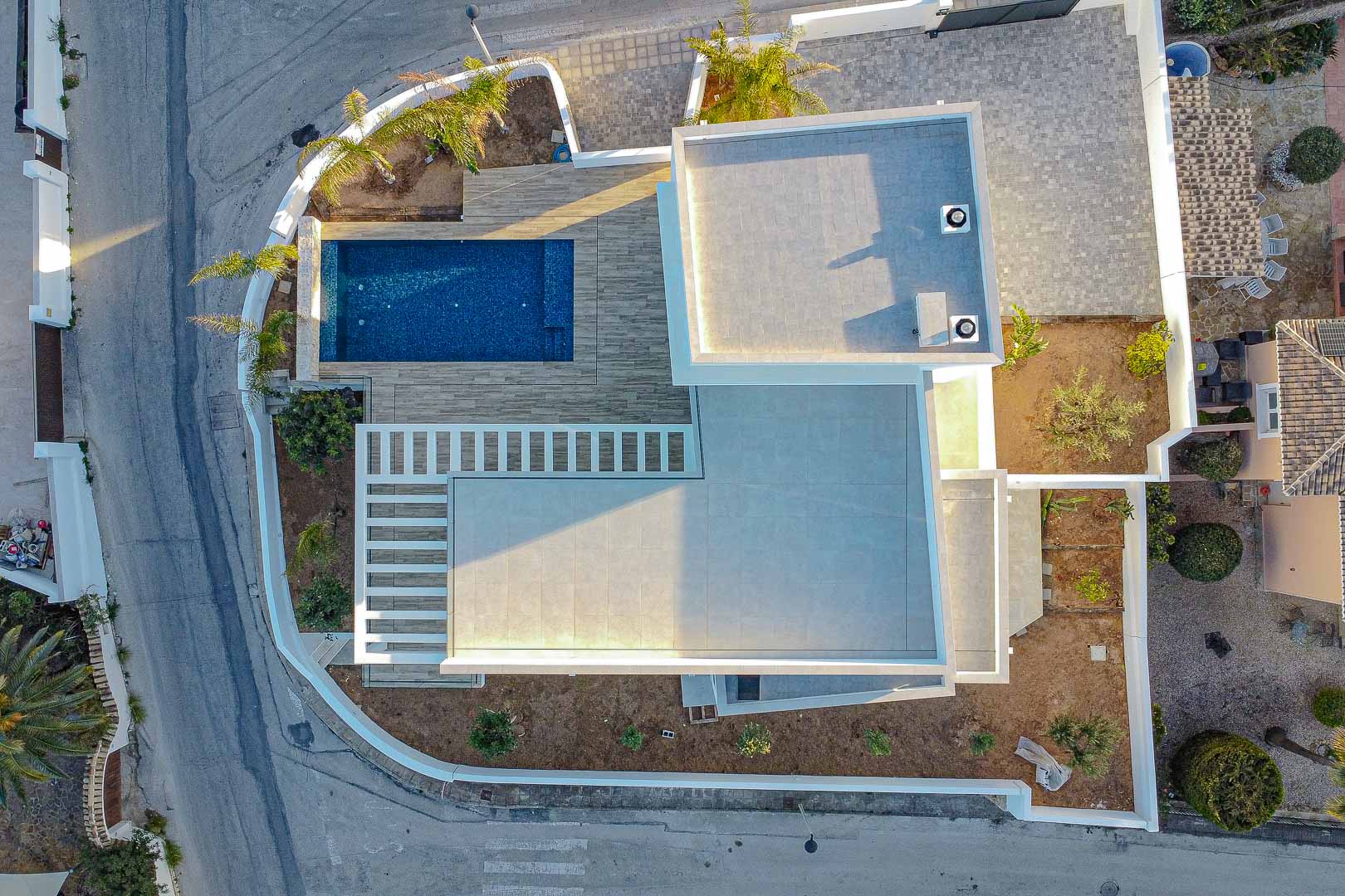 Aerial view of modern villa in Benimeit featuring a blue pool and gray tiled terraces.